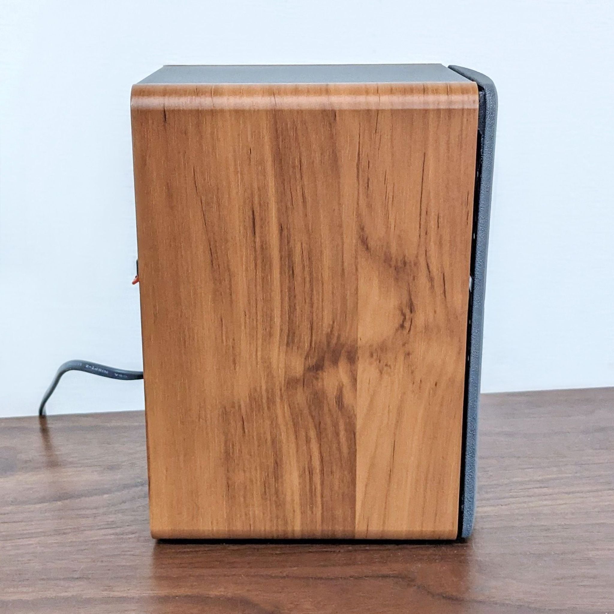 Edifier bookshelf speaker with wood finish and black accents on a table, representing quality audio equipment.
