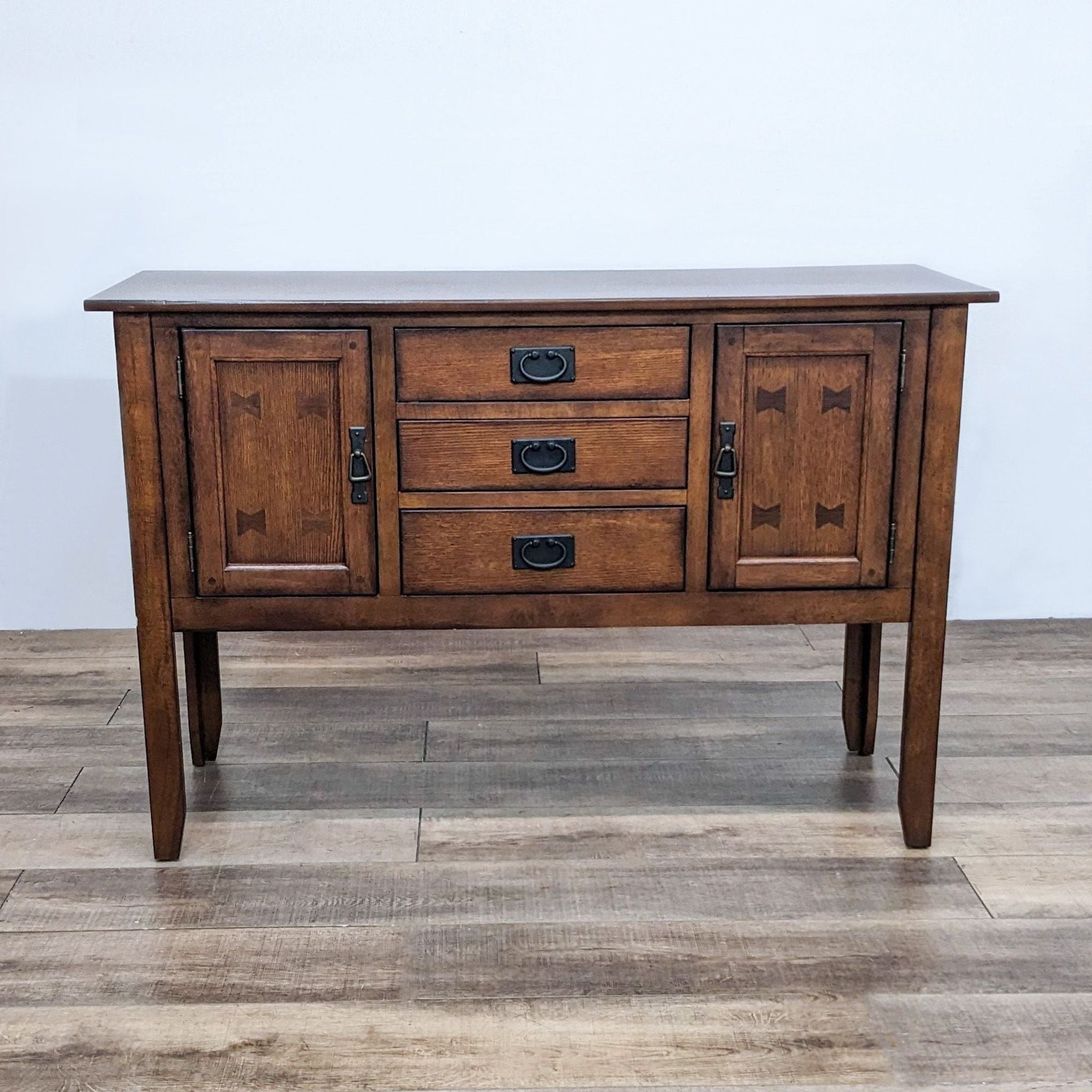 Alt text 1: Reperch brand sideboard with bow tie inlays, closed cabinet doors and central drawers, on a wooden floor.
