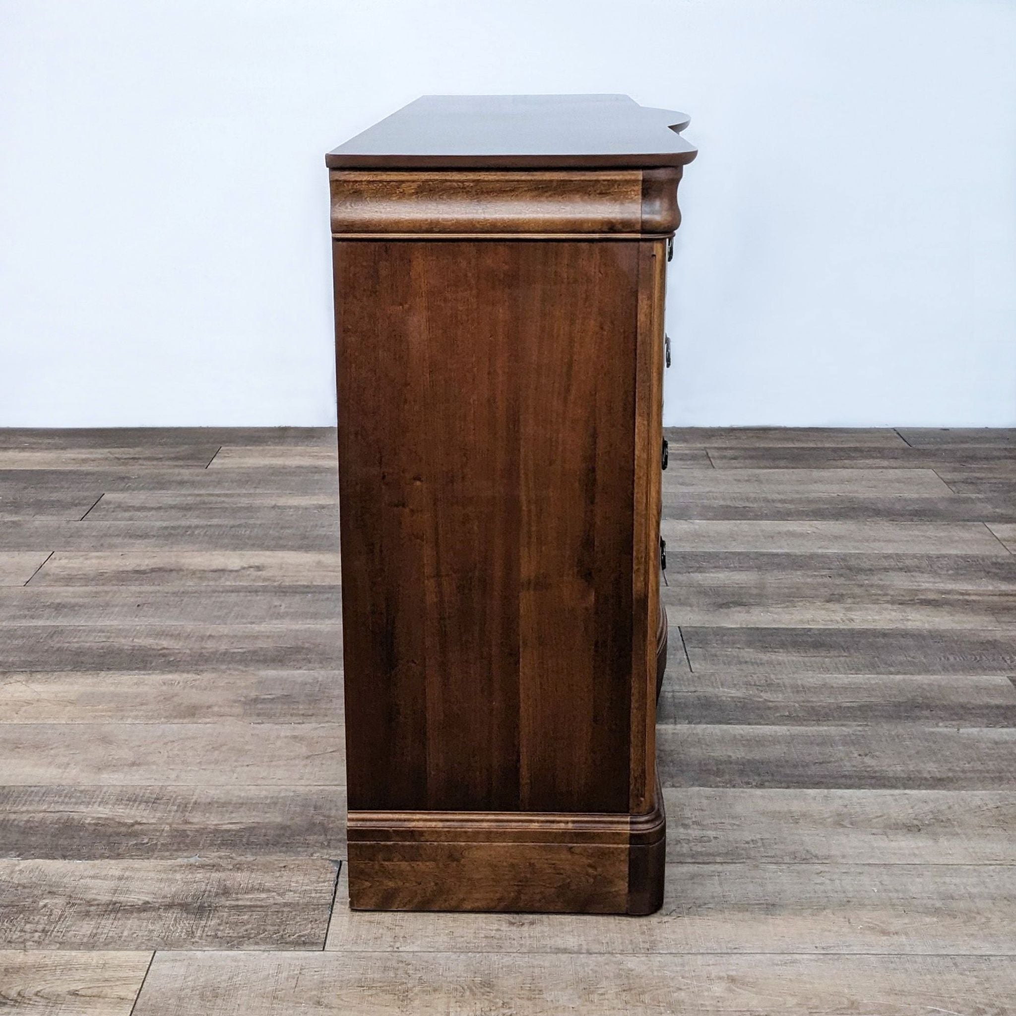 Side view of a Reperch traditional curved 12-drawer dresser with metal pulls on a wooden floor.