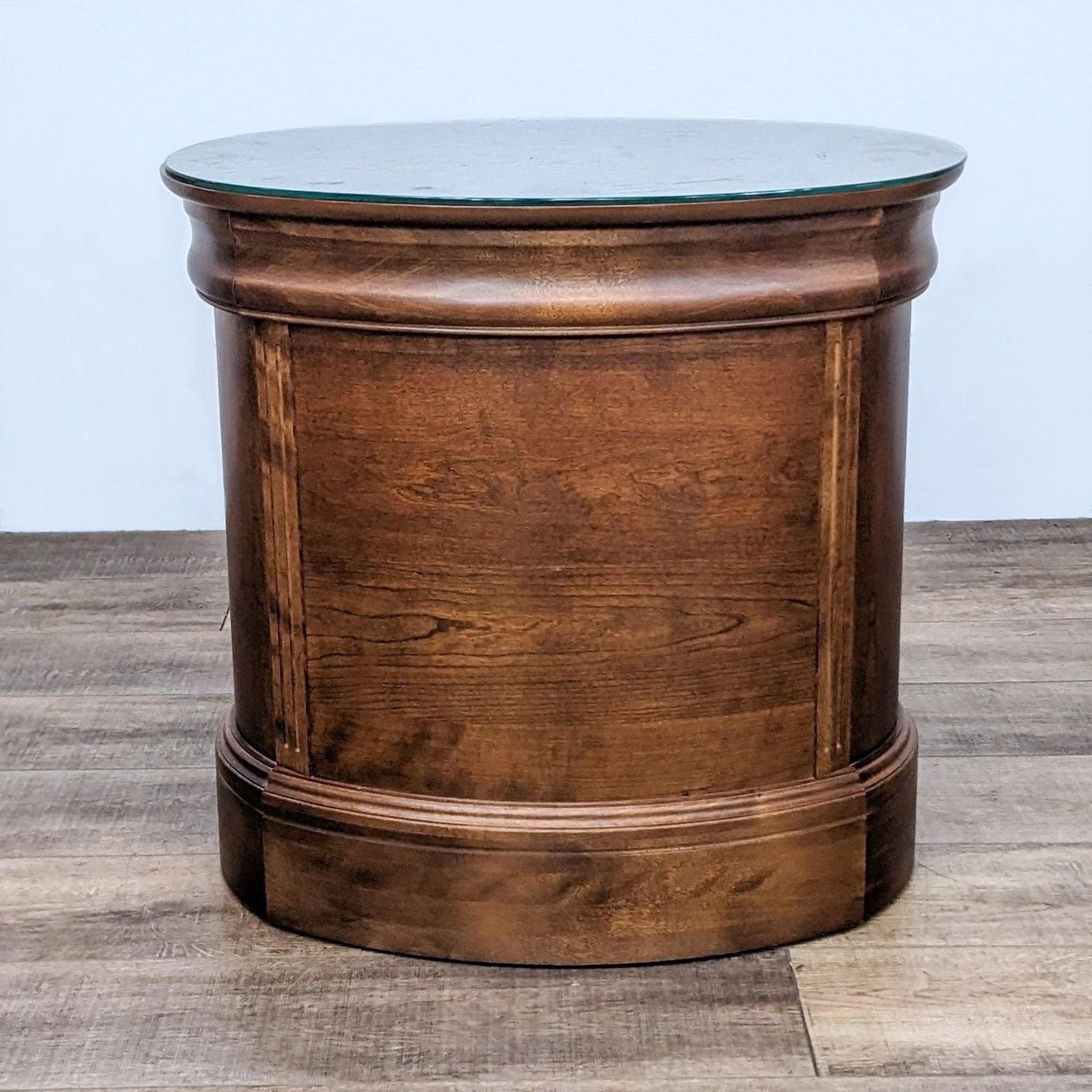 Reperch end table with a cylindrical wooden base and a round glass protective top on a wooden floor.