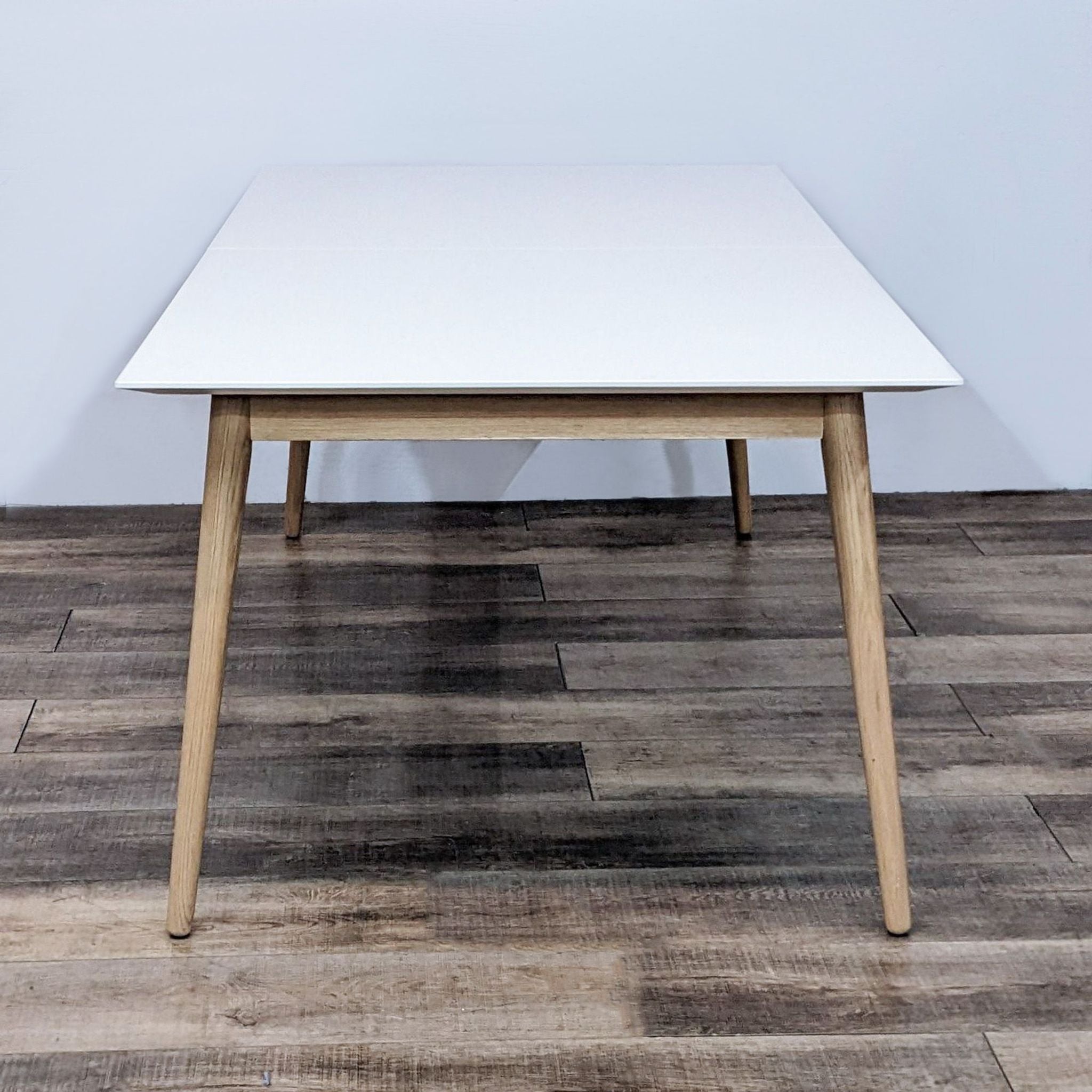BoConcept Milano modern minimalistic dining table, showcasing a compact sleek white tabletop with warm wooden legs.