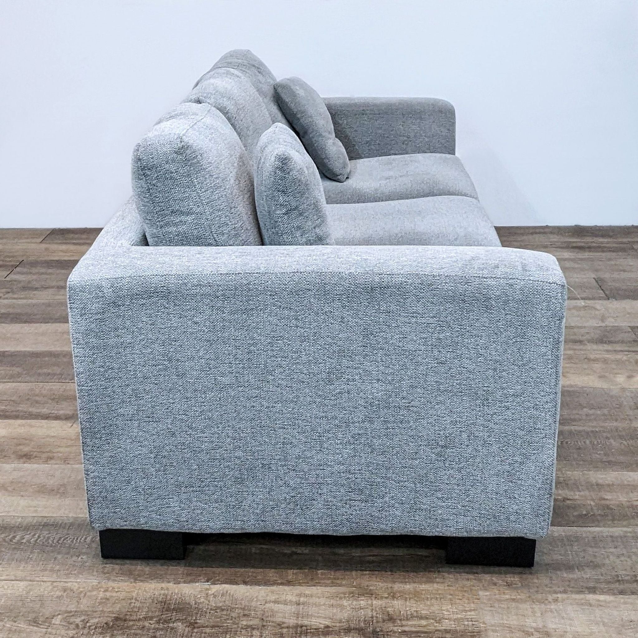 Side view of a Reperch brand 3-seat compact gray fabric sofa with plush cushions and dark wood feet.