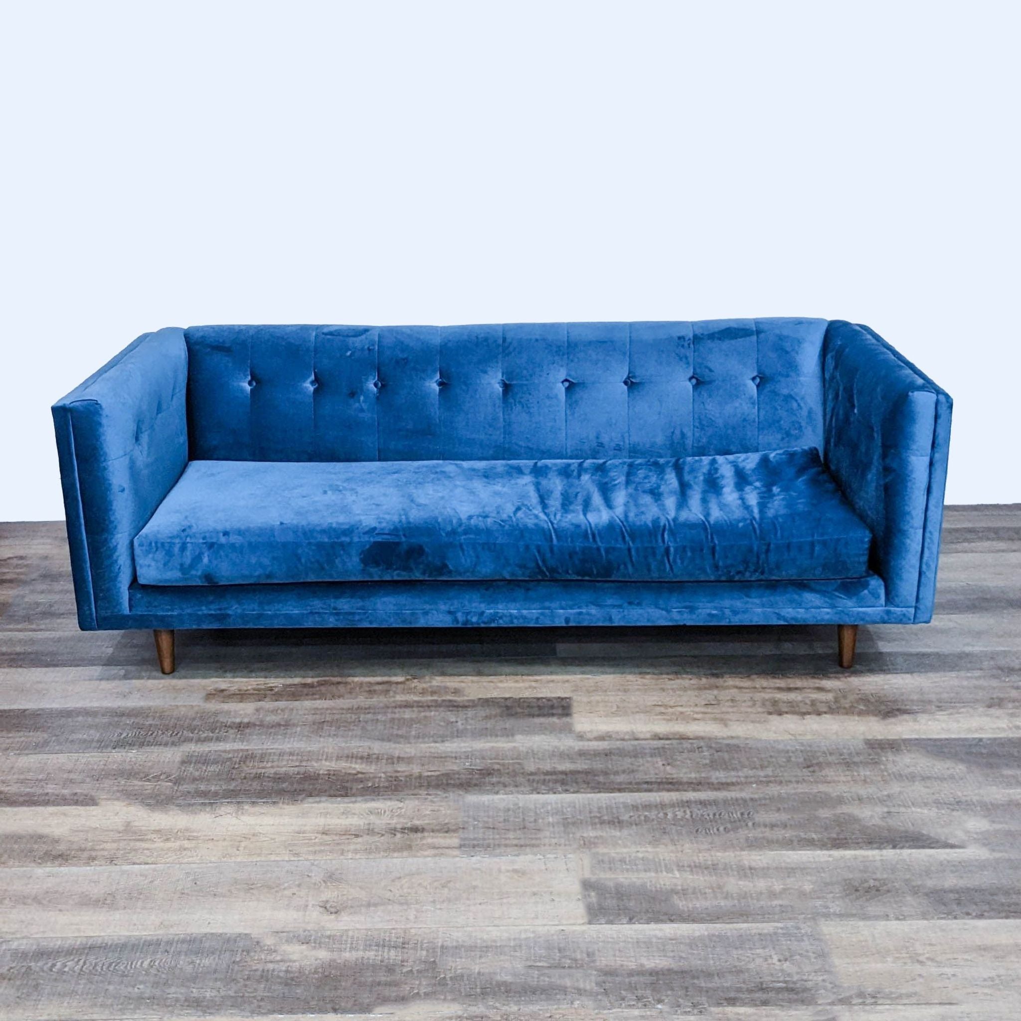 West Elm blue velvet sofa, 3-seat with tufted back and tapered wood feet.