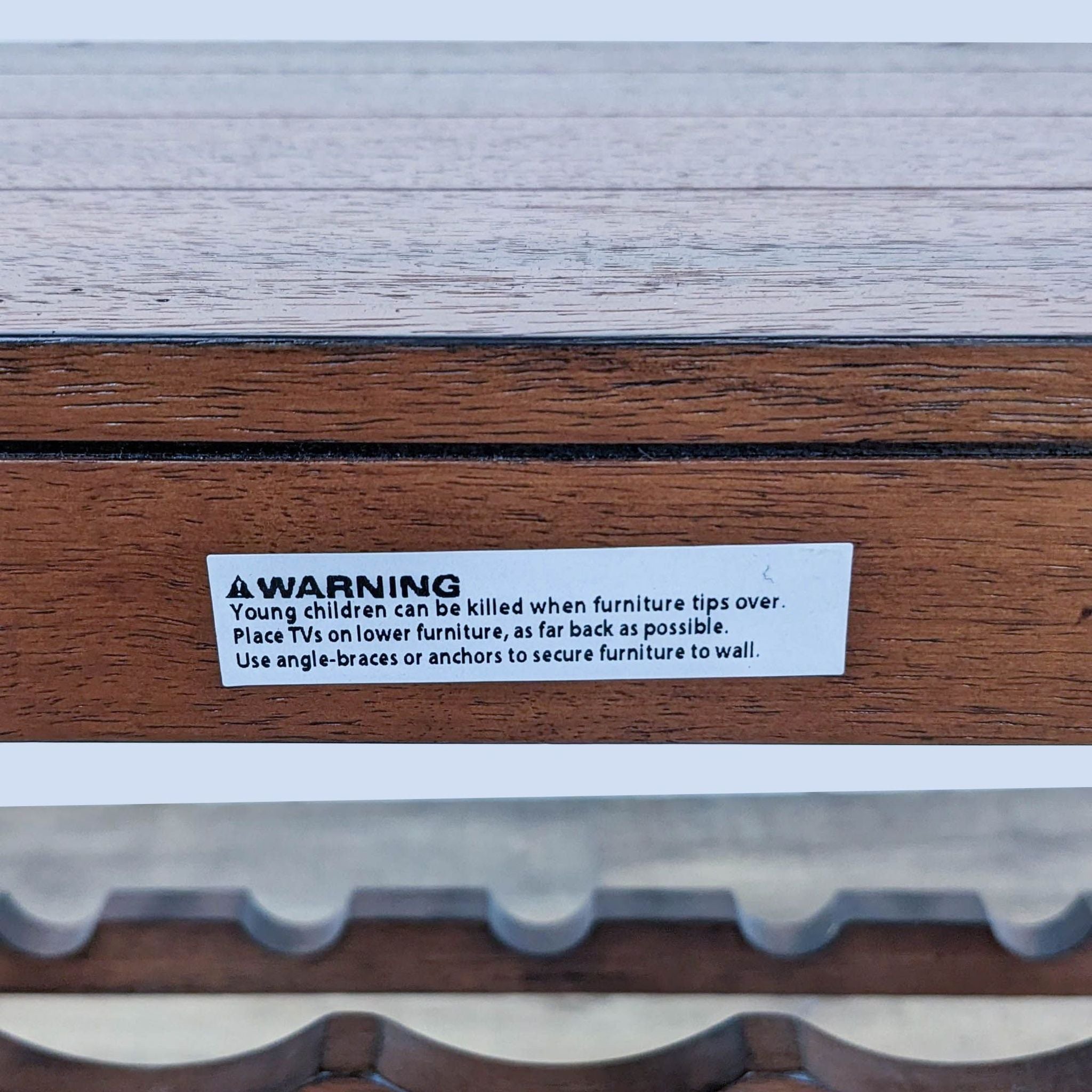 Warning label on Reperch furniture advising to secure to wall to prevent tipping.