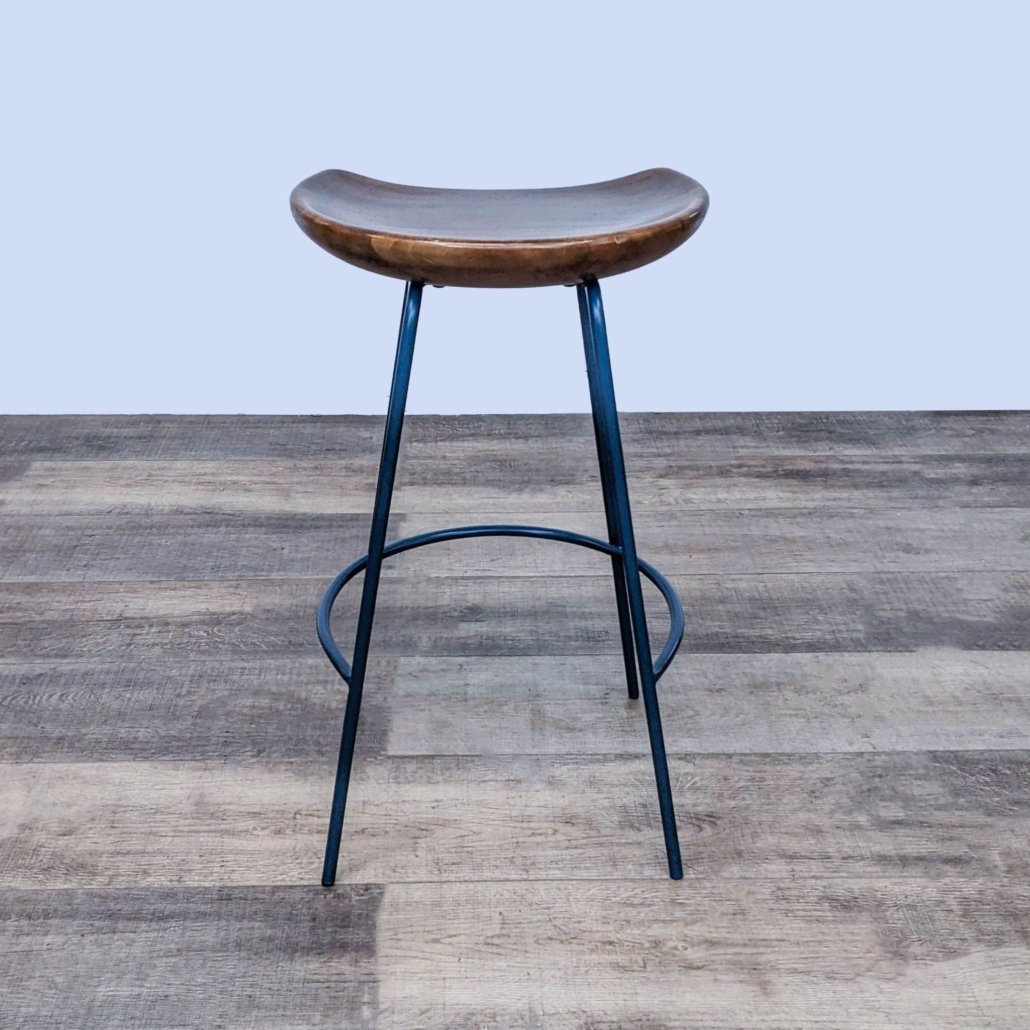 West Elm Alden Counter Stool with solid wood seat and black steel base, shown from the front.