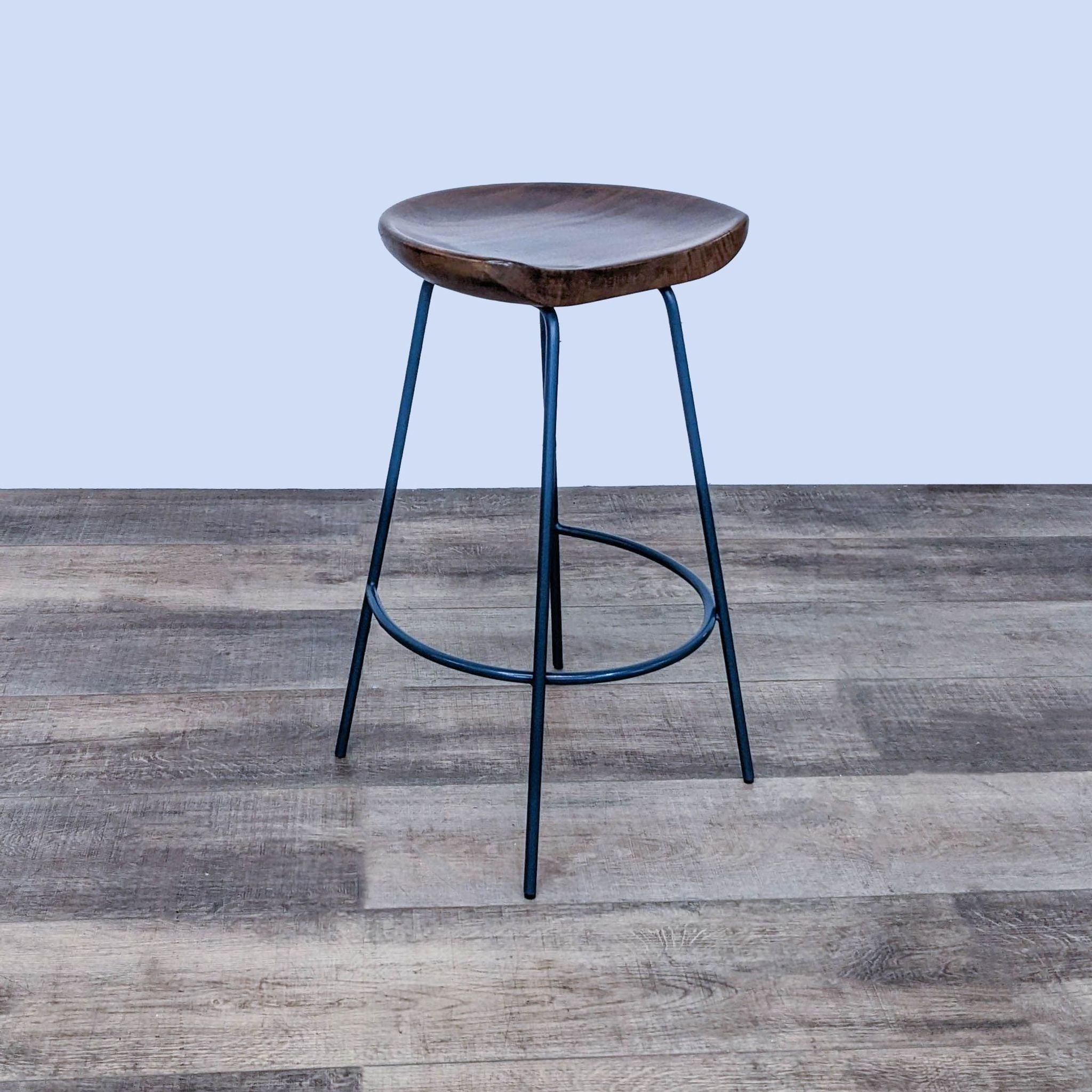 West Elm's Alden solid wood bucket seat counter stool on sleek black steel base, displayed in profile.