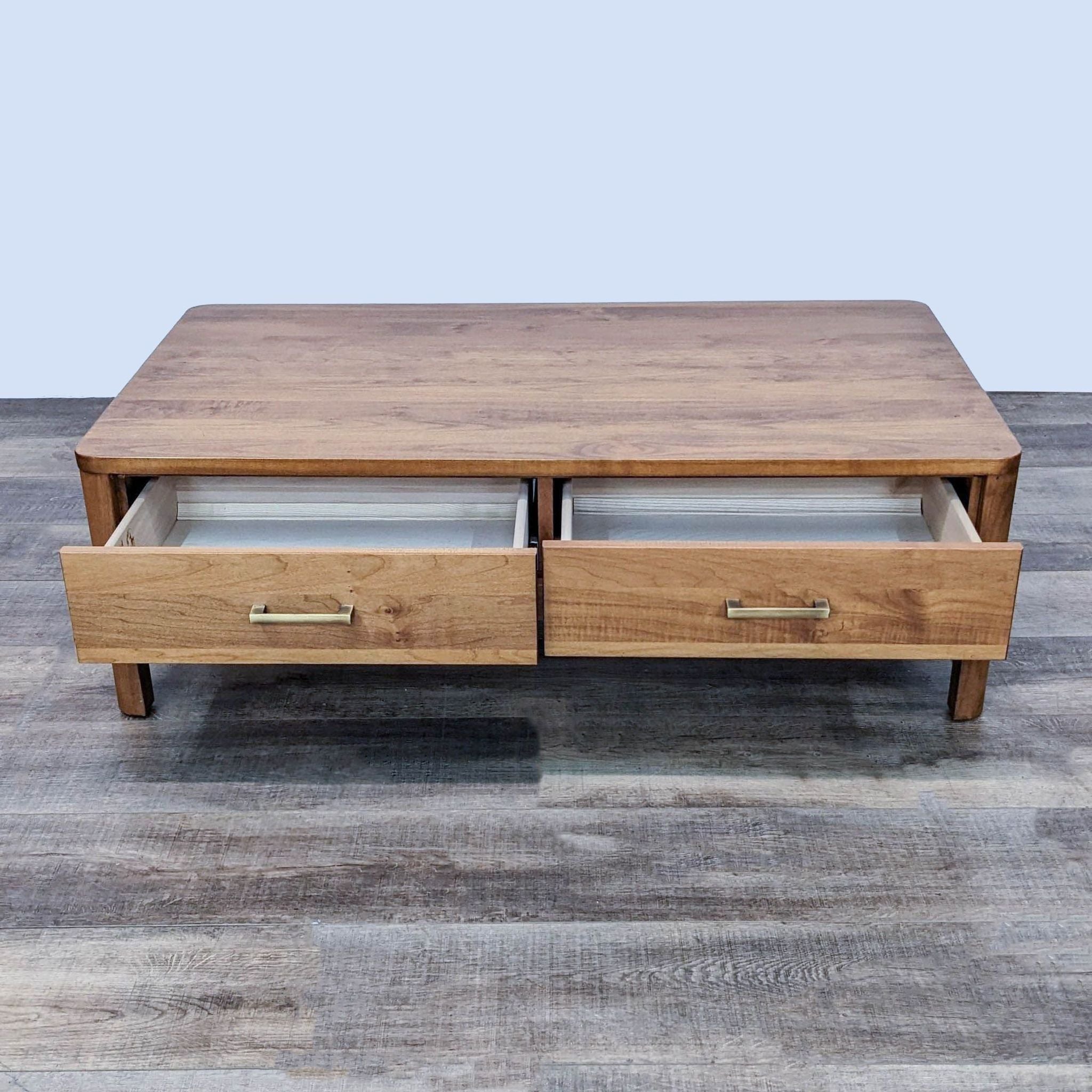 Wood Castle coffee table with two open drawers revealing storage space, placed on a textured floor.