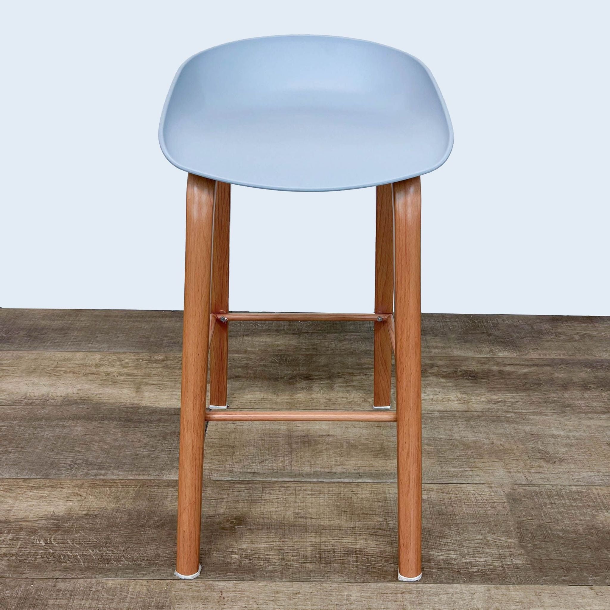 Gray Reperch barstool with minimalistic molded seat on wooden frame, front view.