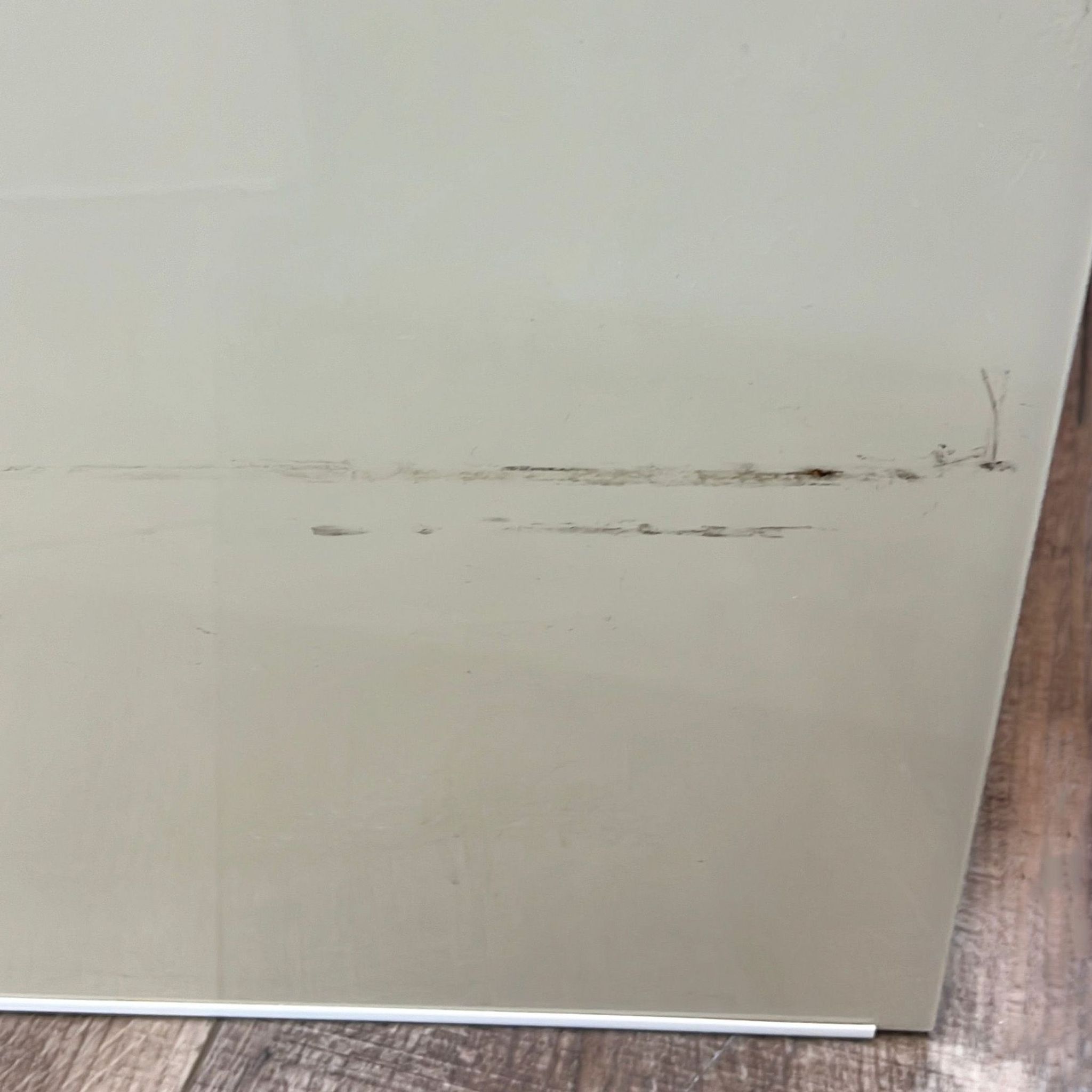 Close-up of a damaged cream-colored Reperch end table showing significant wear on the surface.