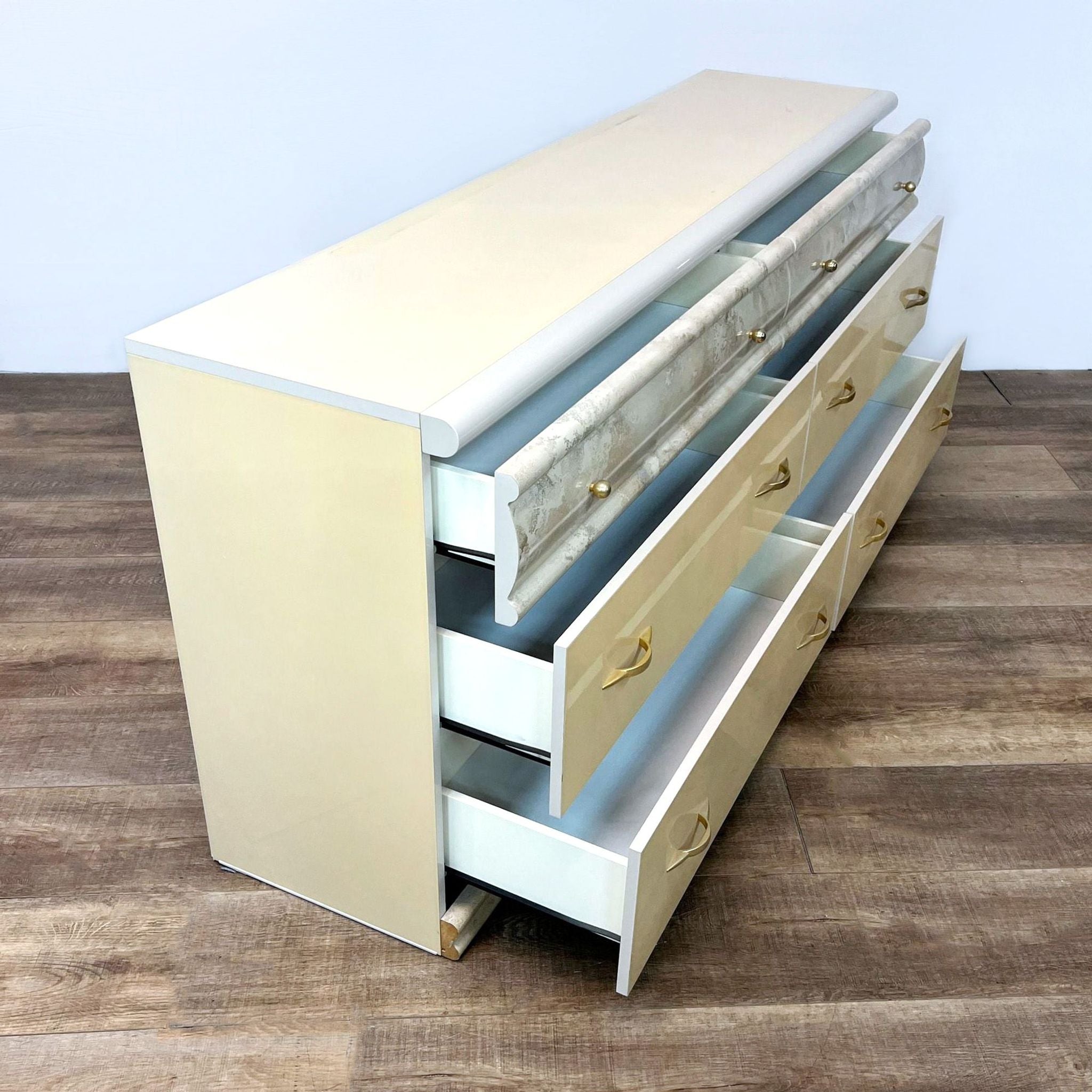 Open side view of Reperch Italian 6-drawer cream dresser showcasing drawers and marble-like accents with gold handles.