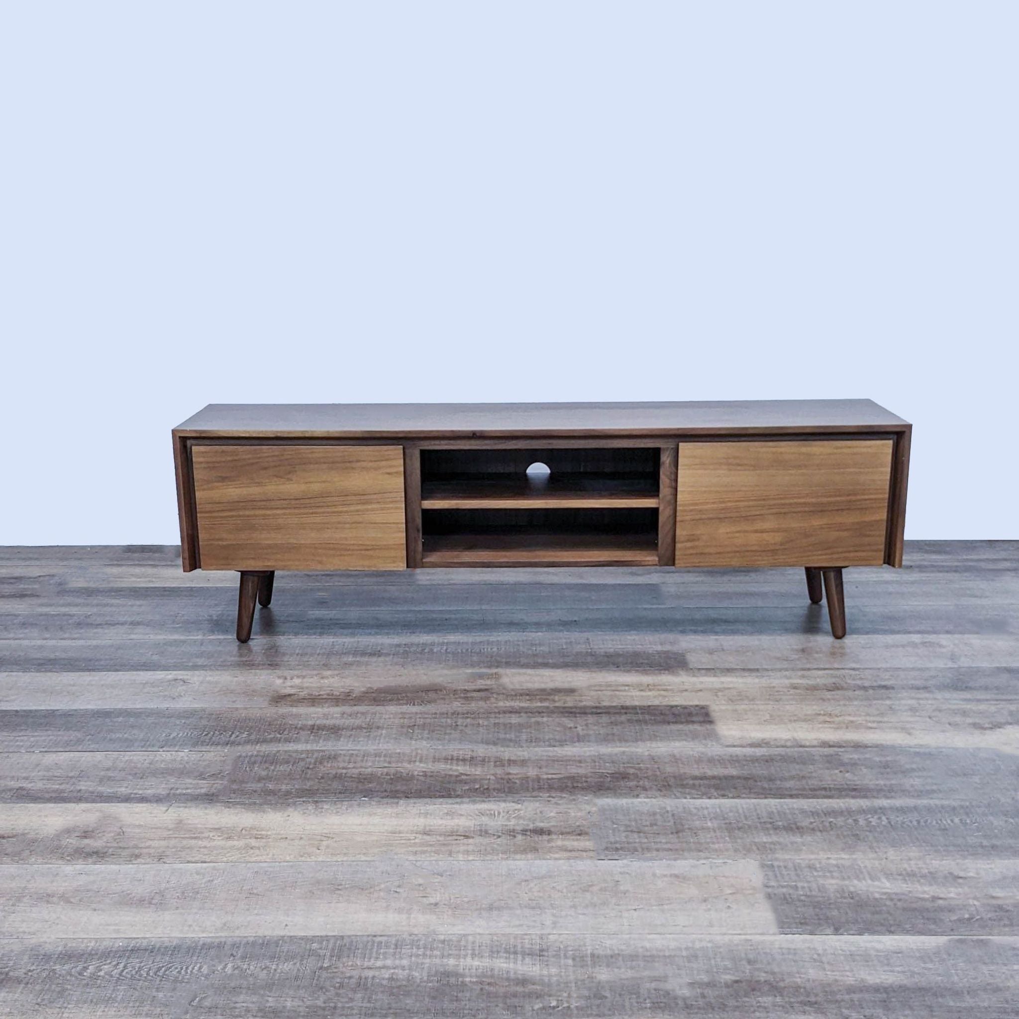 Alt text 1: Article brand Mid-Century Modern entertainment center on a wooden floor, featuring a beveled top, open shelf, and tapered legs.
