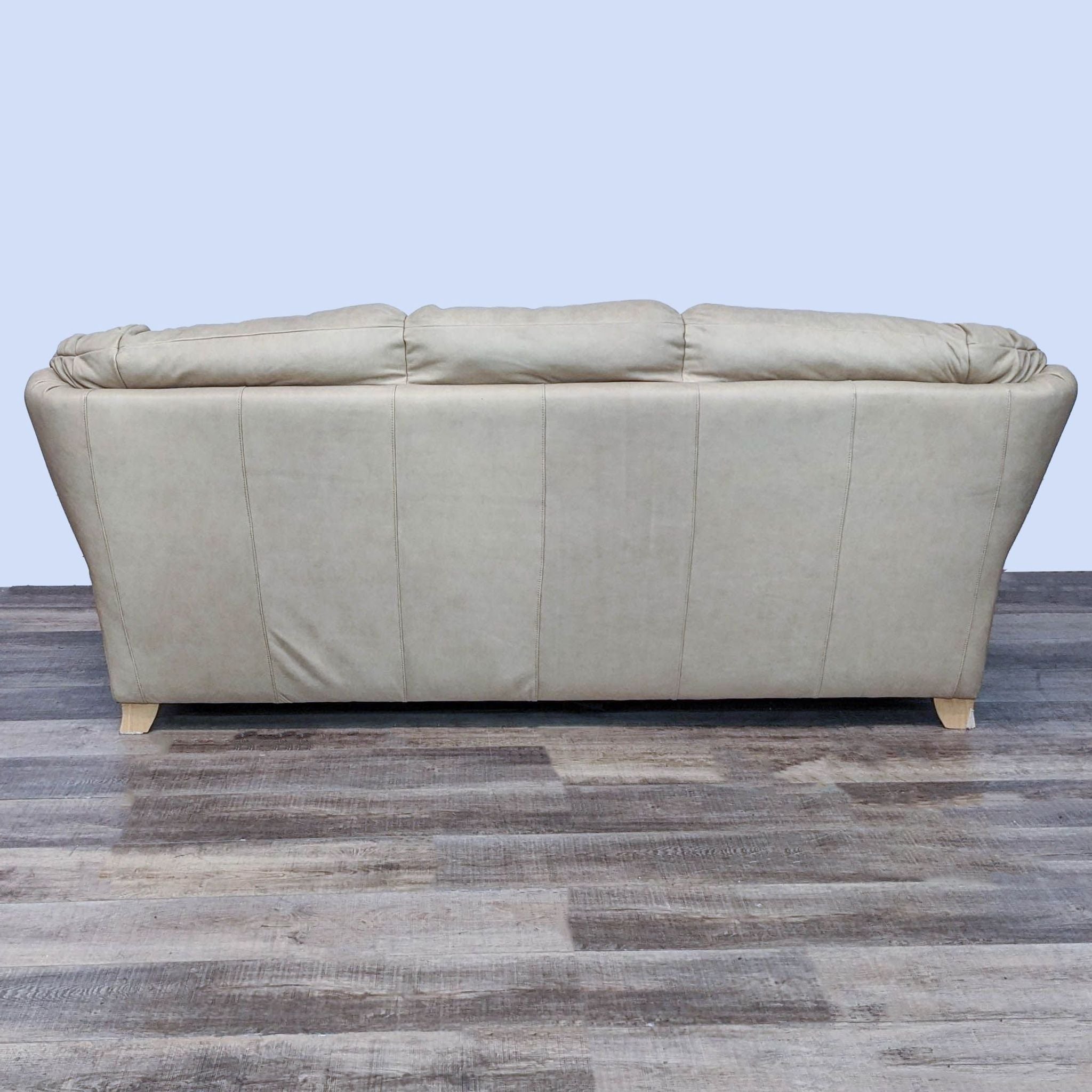 Alt text 2: Rear view of a tan Reperch leather 3-seat sofa showcasing light finish feet and stitched backrest on a grey floor.