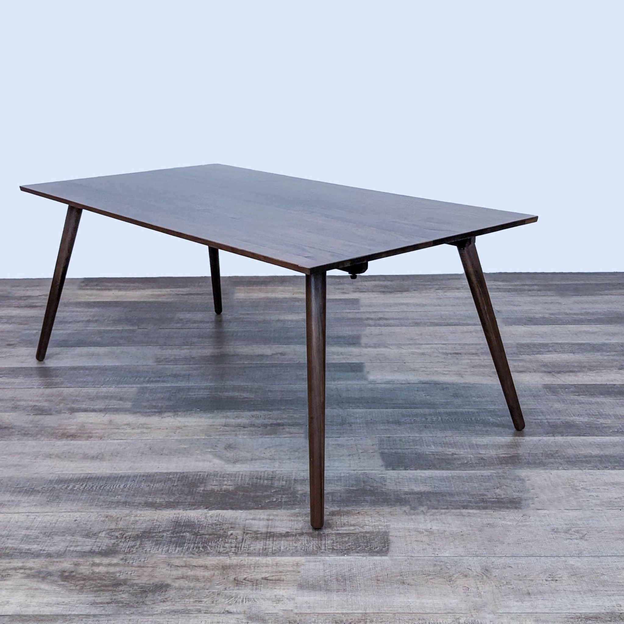 Article Seno Dining Table with mid-century modern design, tapered wooden legs, and clean lines, on a wood floor.
