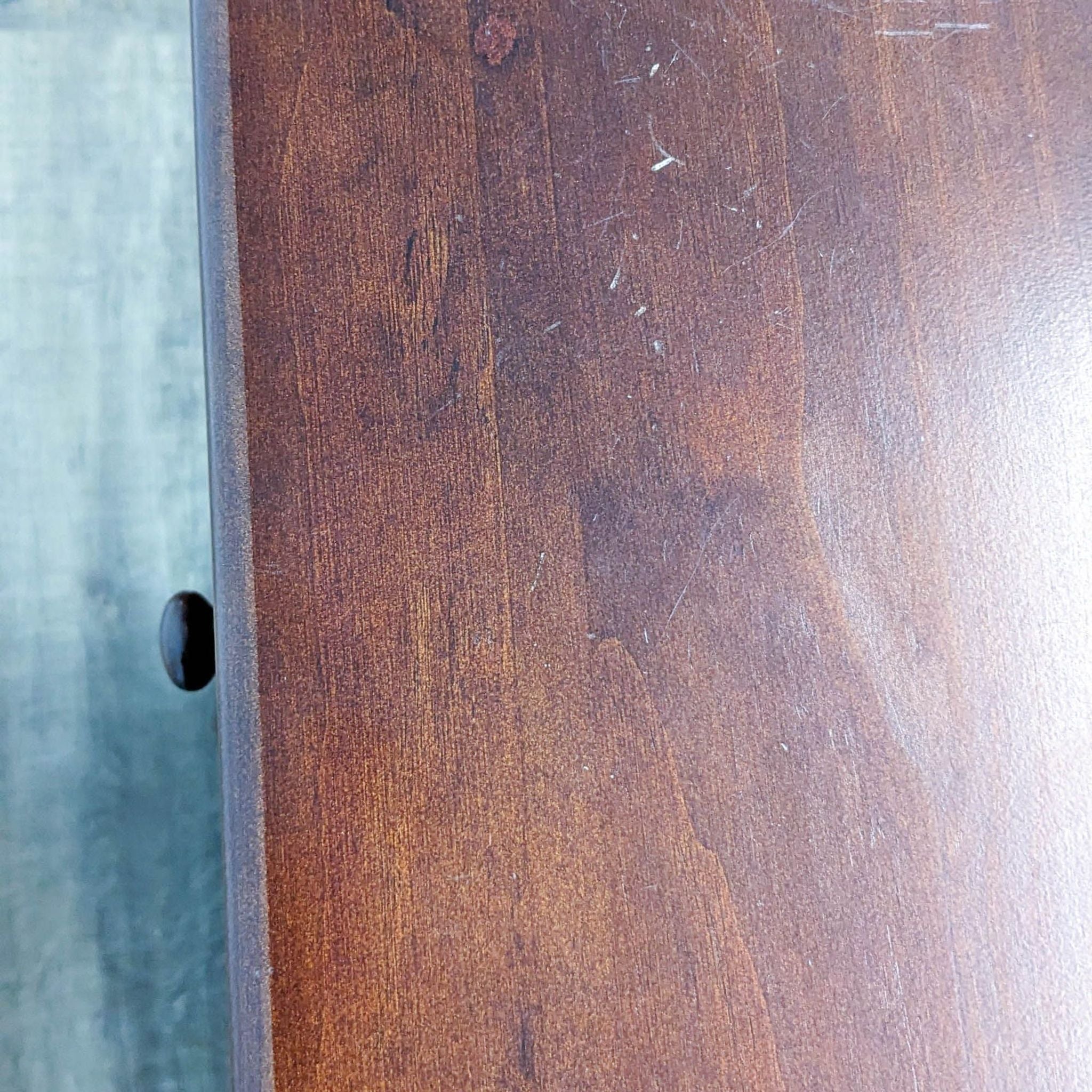 Close-up of the wood texture on a Million Dollar Baby classic dresser with visible scratches.