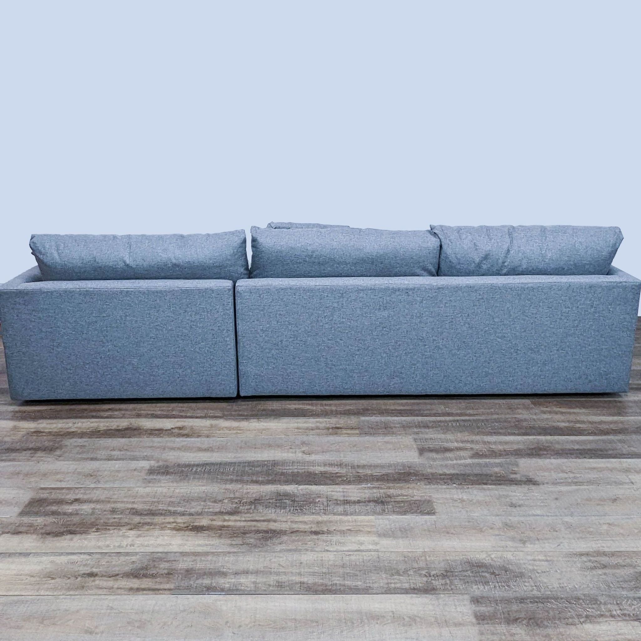 Crate & Barrel gray sectional sofa on a wooden floor with a simple, modern design.