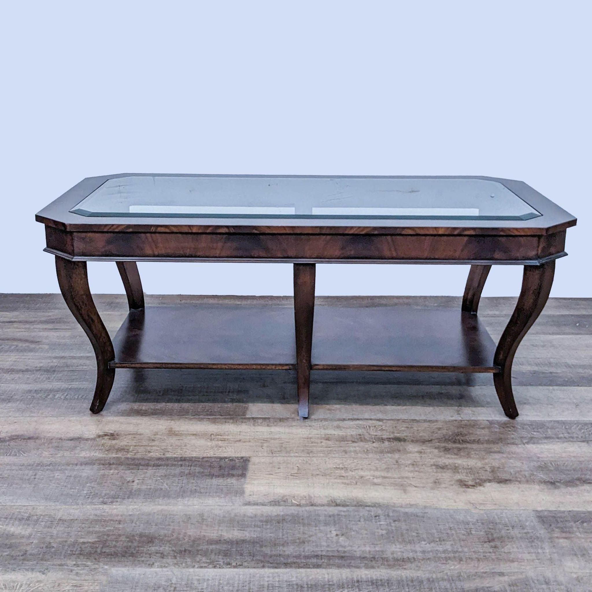 Ethan Allen mahogany coffee table with beveled glass top and curved cabriole legs on a wooden floor.