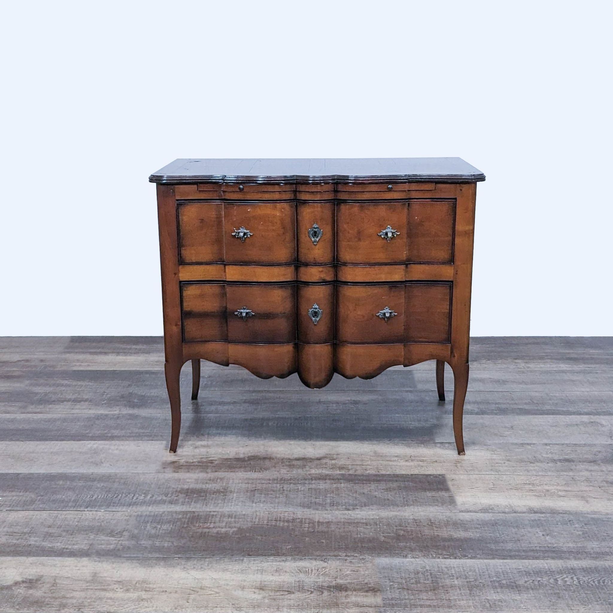 DeBournay two-drawer wooden dresser with curved lines, dovetail joinery, and ornate handles, standing on slender legs.