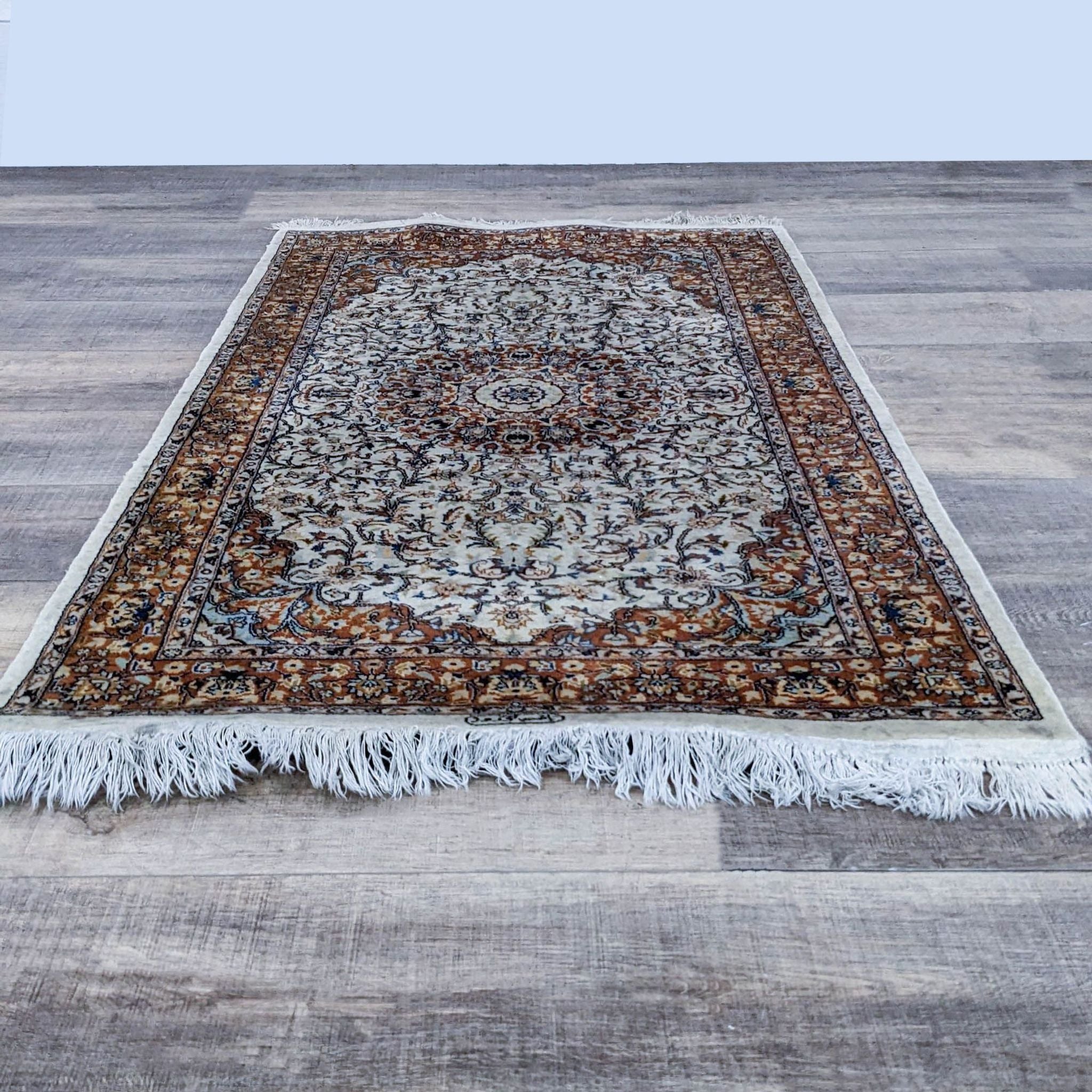 Reperch traditional oriental rug with earth-tone patterns and fringe on a wood floor.