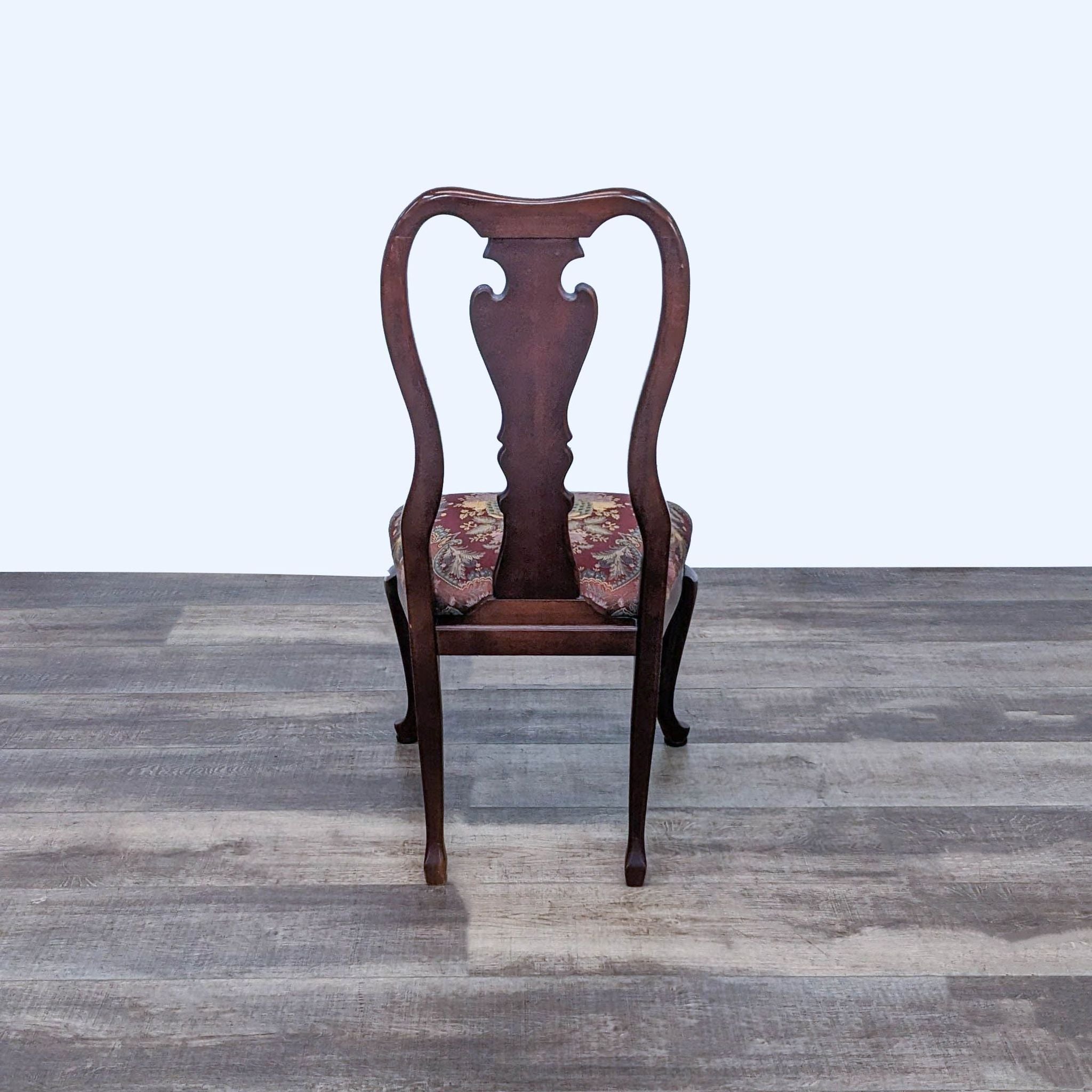 Ethan Allen dining chair with dark wood finish and floral patterned upholstery on a wooden floor.