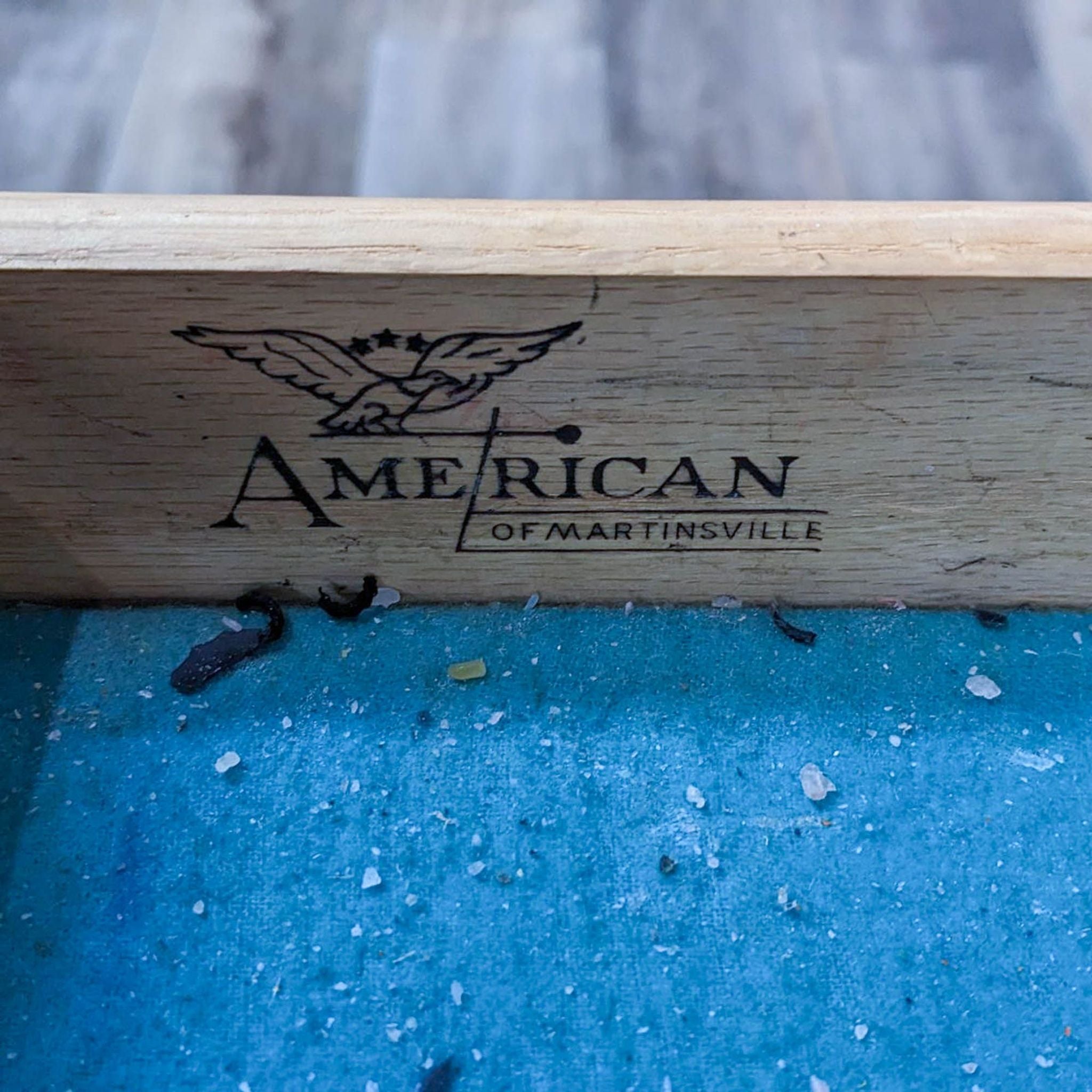 Close-up of the American of Martinsville logo on a wooden surface.
