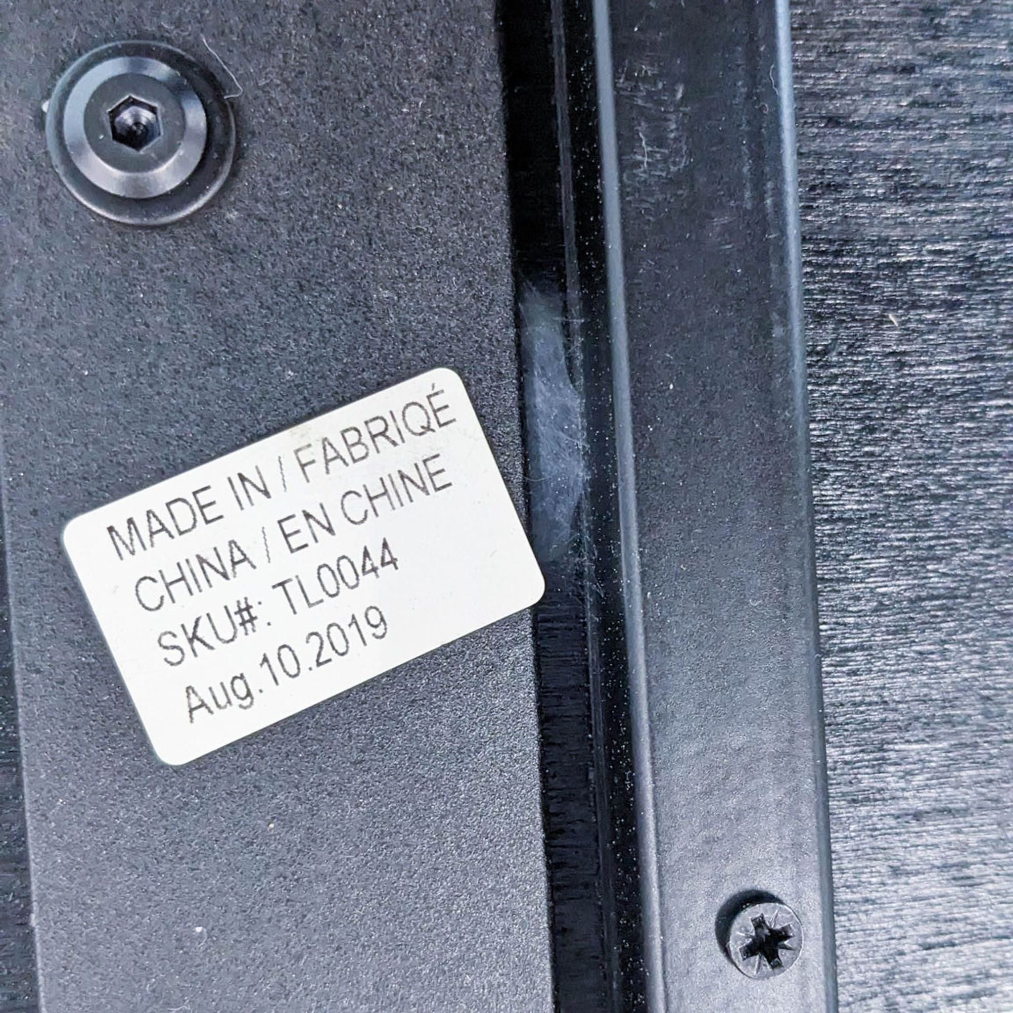 Close-up of a Reperch coffee table's label showing 'Made in China' and SKU number on metal leg with a wood-patterned background.