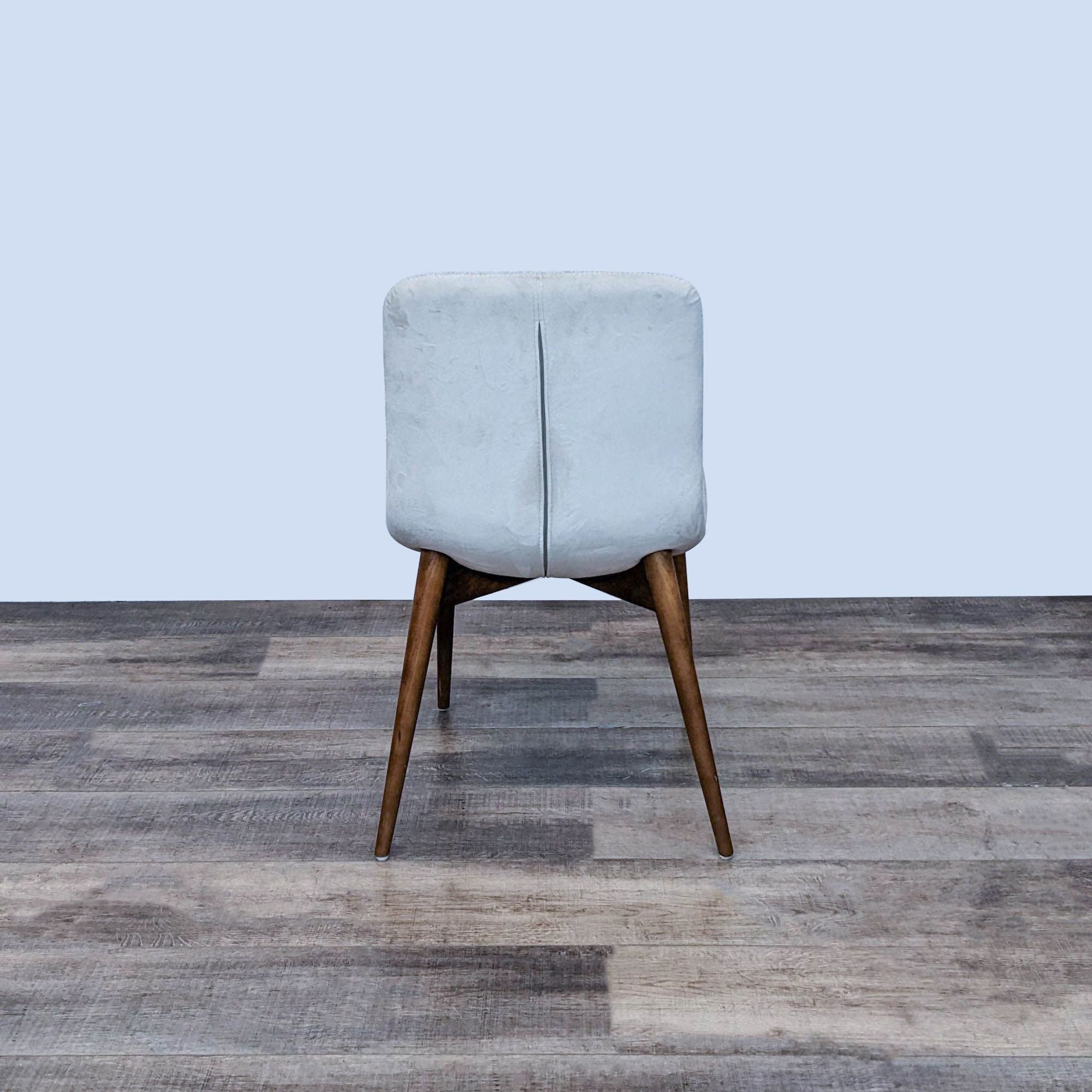 Front-facing Reperch chair showing its light fabric upholstery and wooden legs on a wooden floor. 