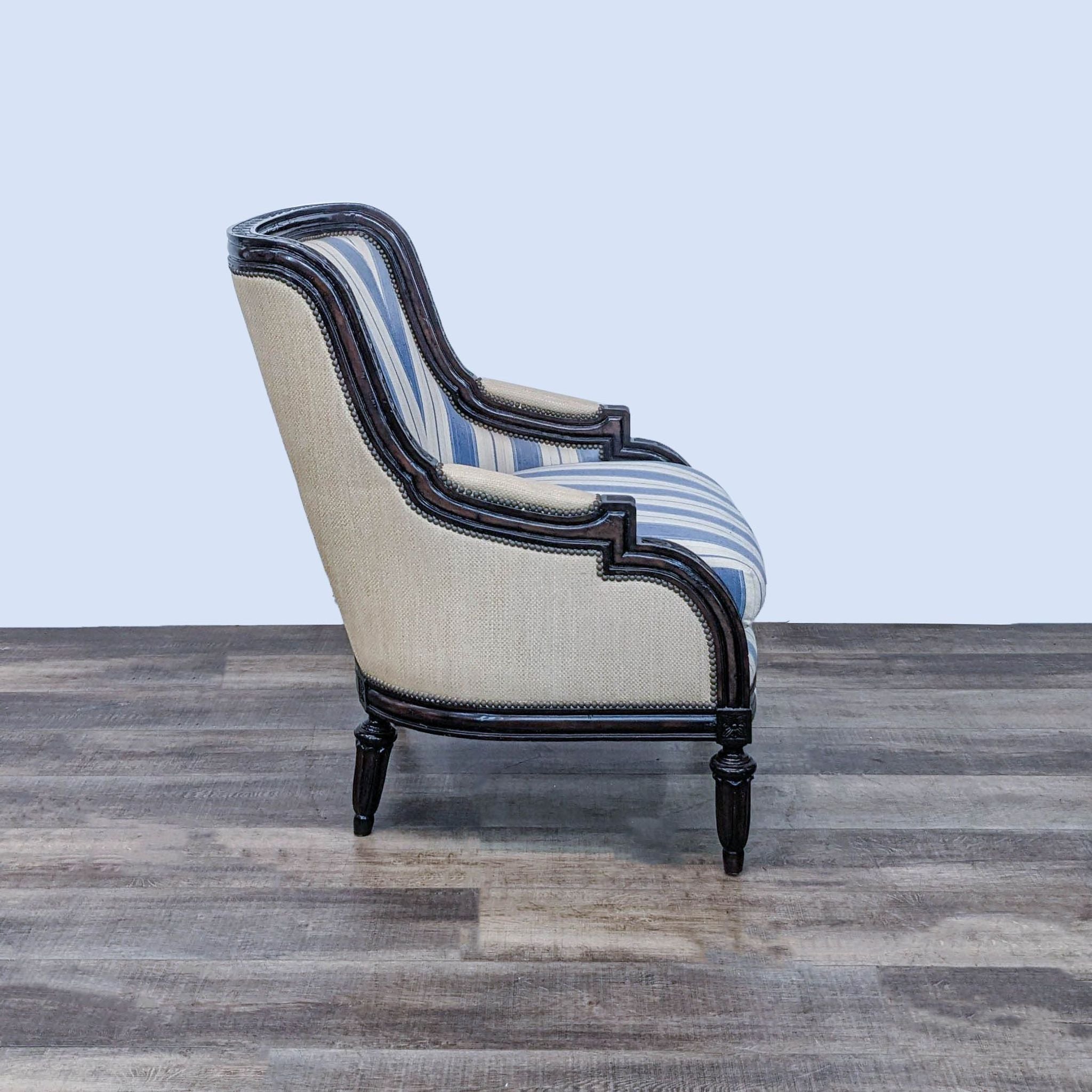 Classic Marge Carson lounge chair, profile view, featuring cool stripes, nailhead accents, and ornate wooden legs.