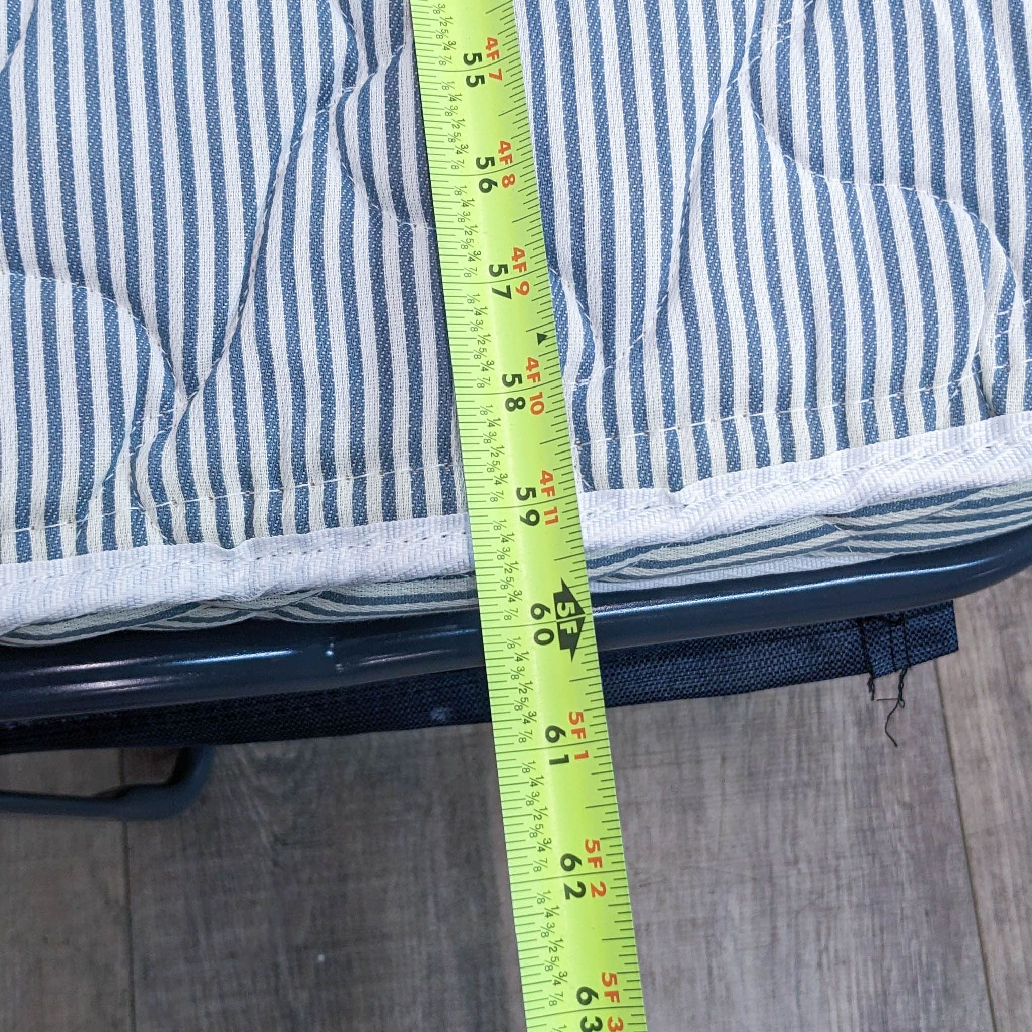 Measuring tape showing the thickness of Crate & Barrel sleeper sofa's mattress with striped cover.
