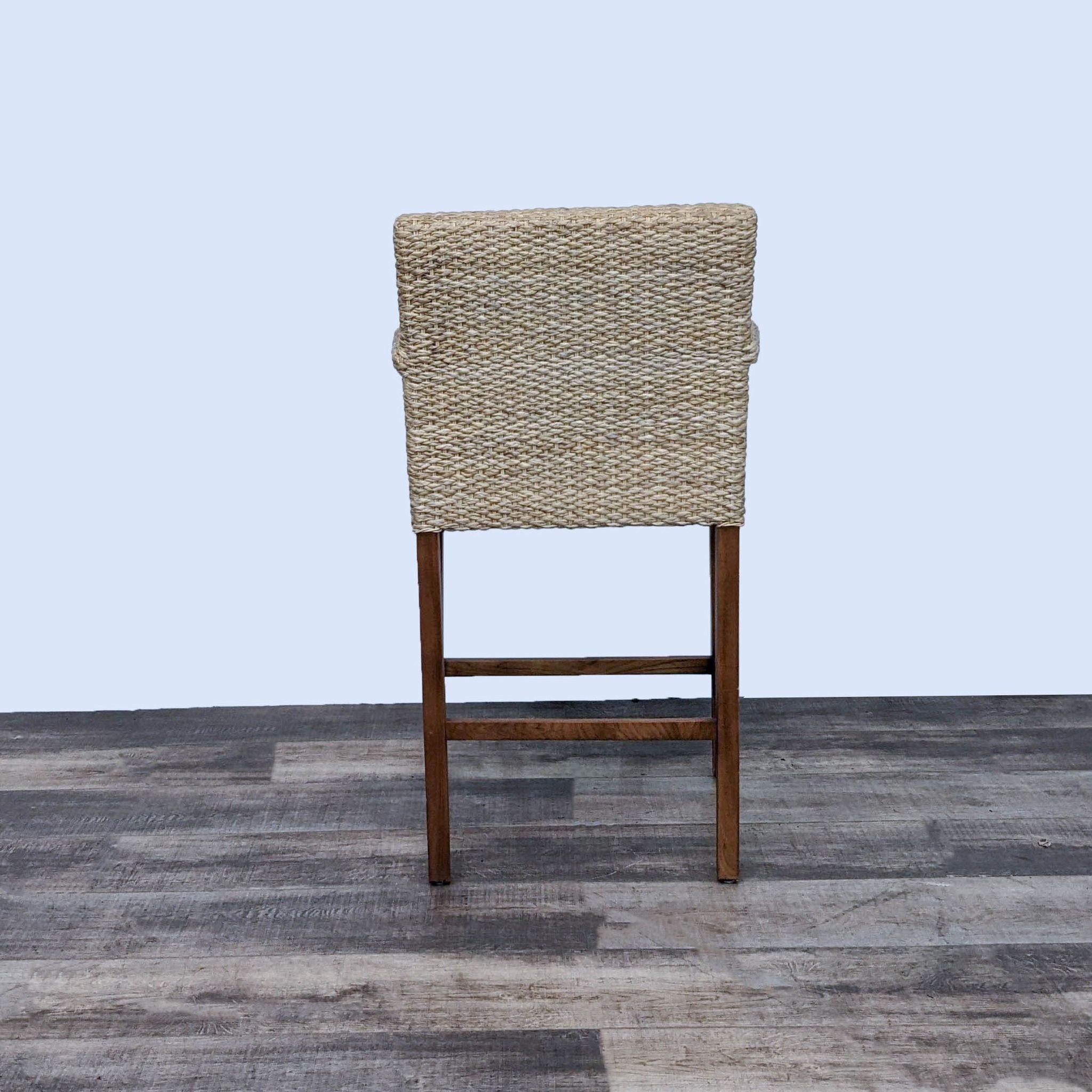 Reperch seagrass stool with green and blue plaid cushion on wooden frame, against a gray floor and white background.
