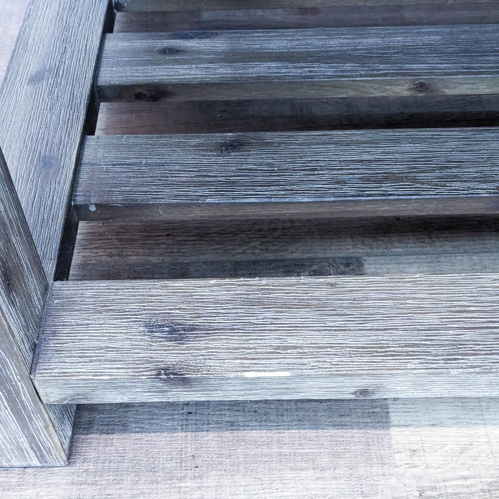 Close-up of Macy's rustic coffee table detailing wire-brushed taupe finish with grey undertones on wood slats.