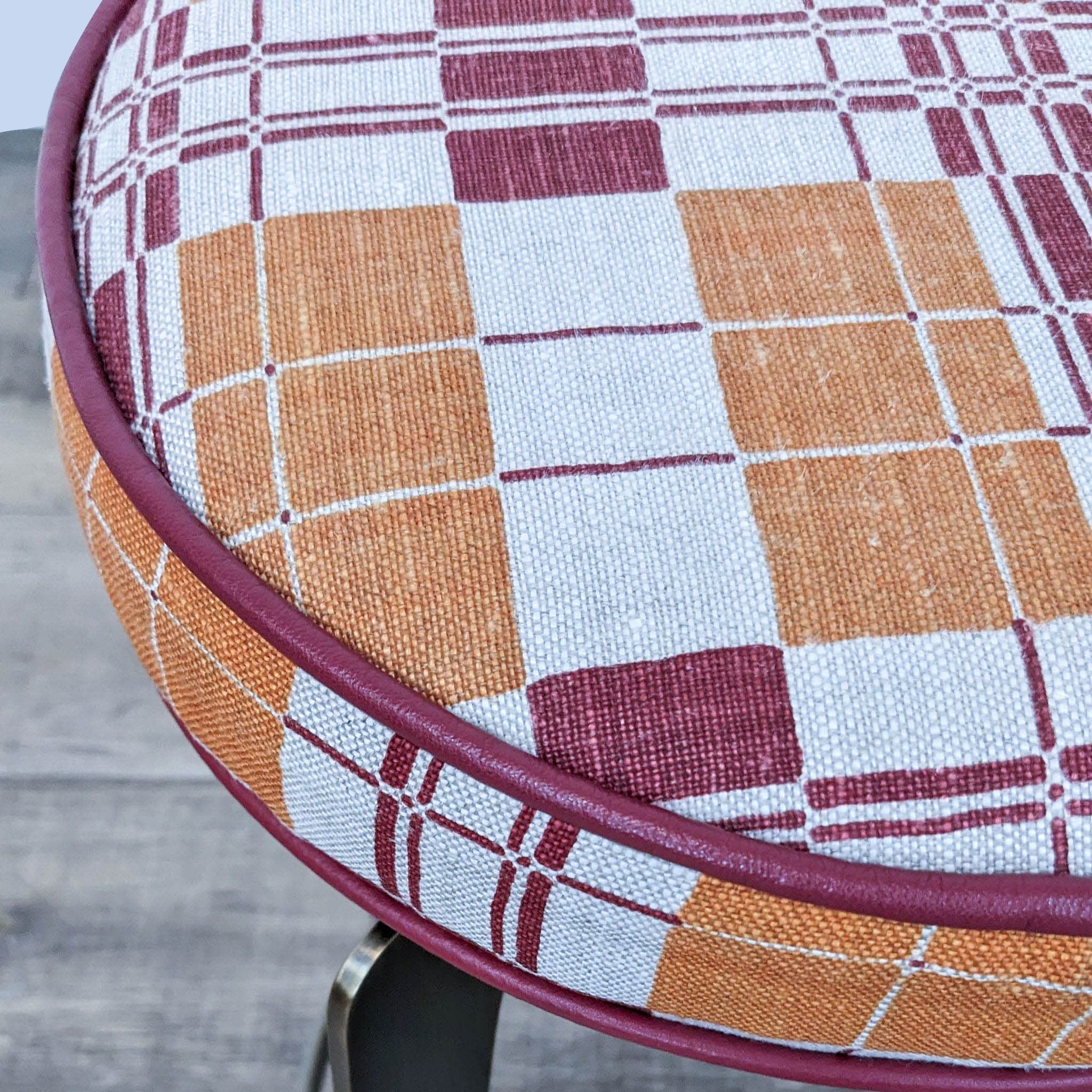 Close-up of Reperch geometric fabric stool with padded top and bronze metal frame.