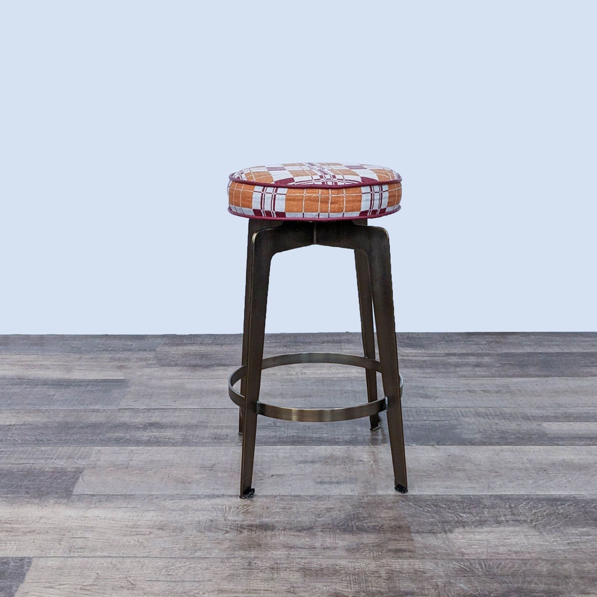 Reperch counter stool with a whimsical geometric-patterned fabric top and bronze metal frame.