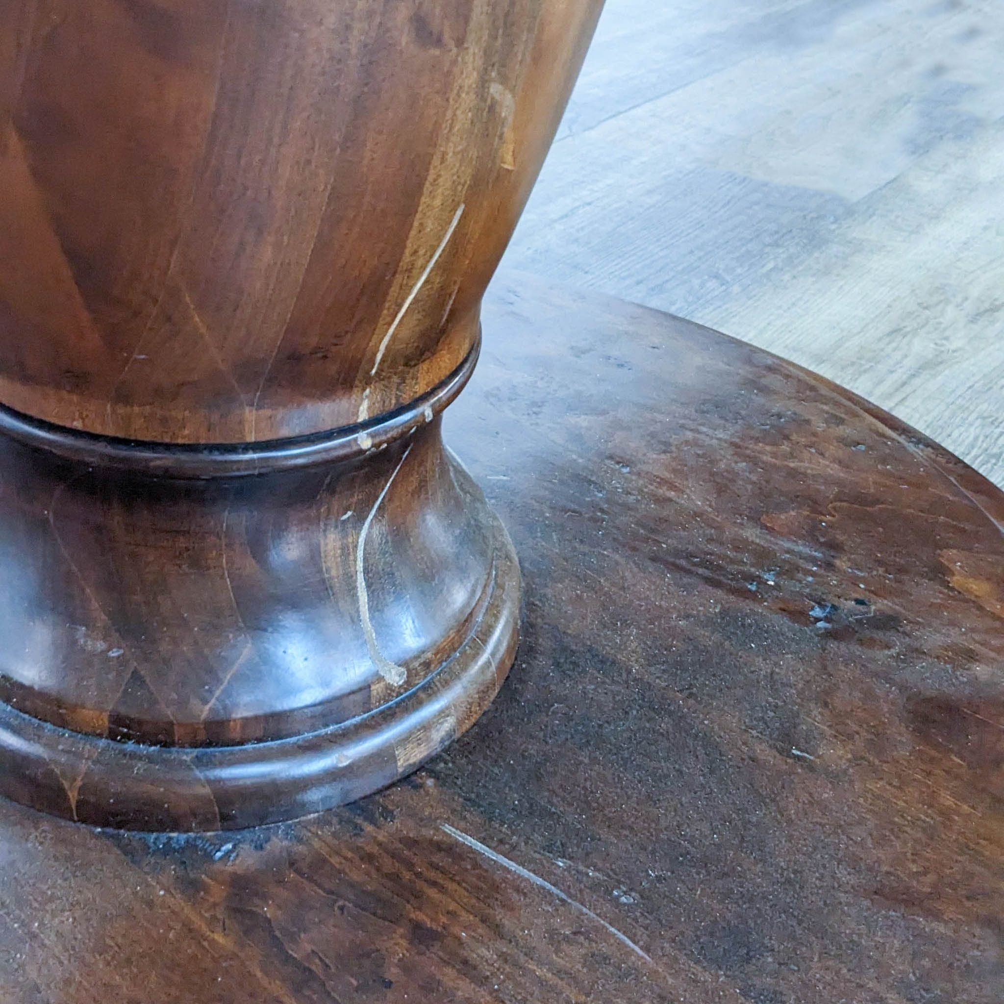 Close-up of the double pedestal base of a Reperch dark wooden dining table with visible wood grain and carving details.