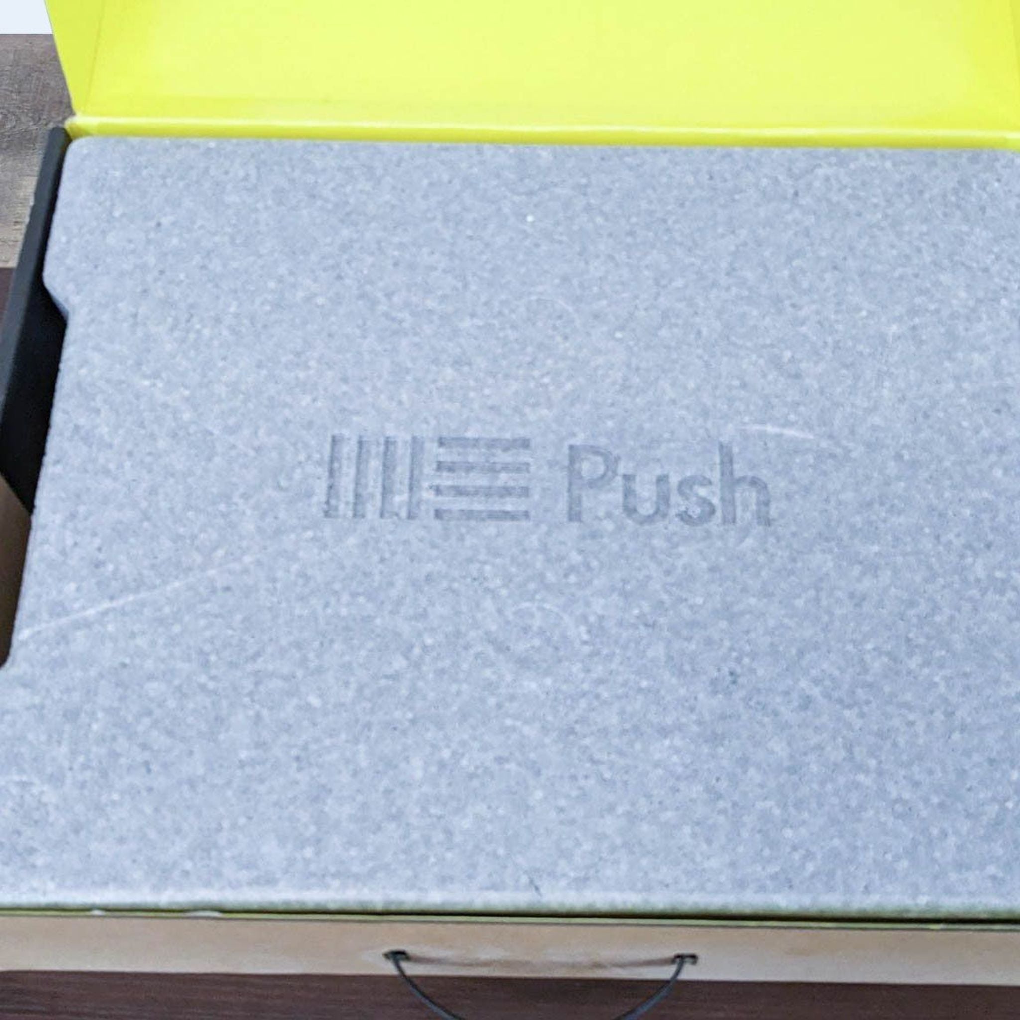 Ableton Push MIDI controller's original grey foam packaging with logo, viewed partially open.