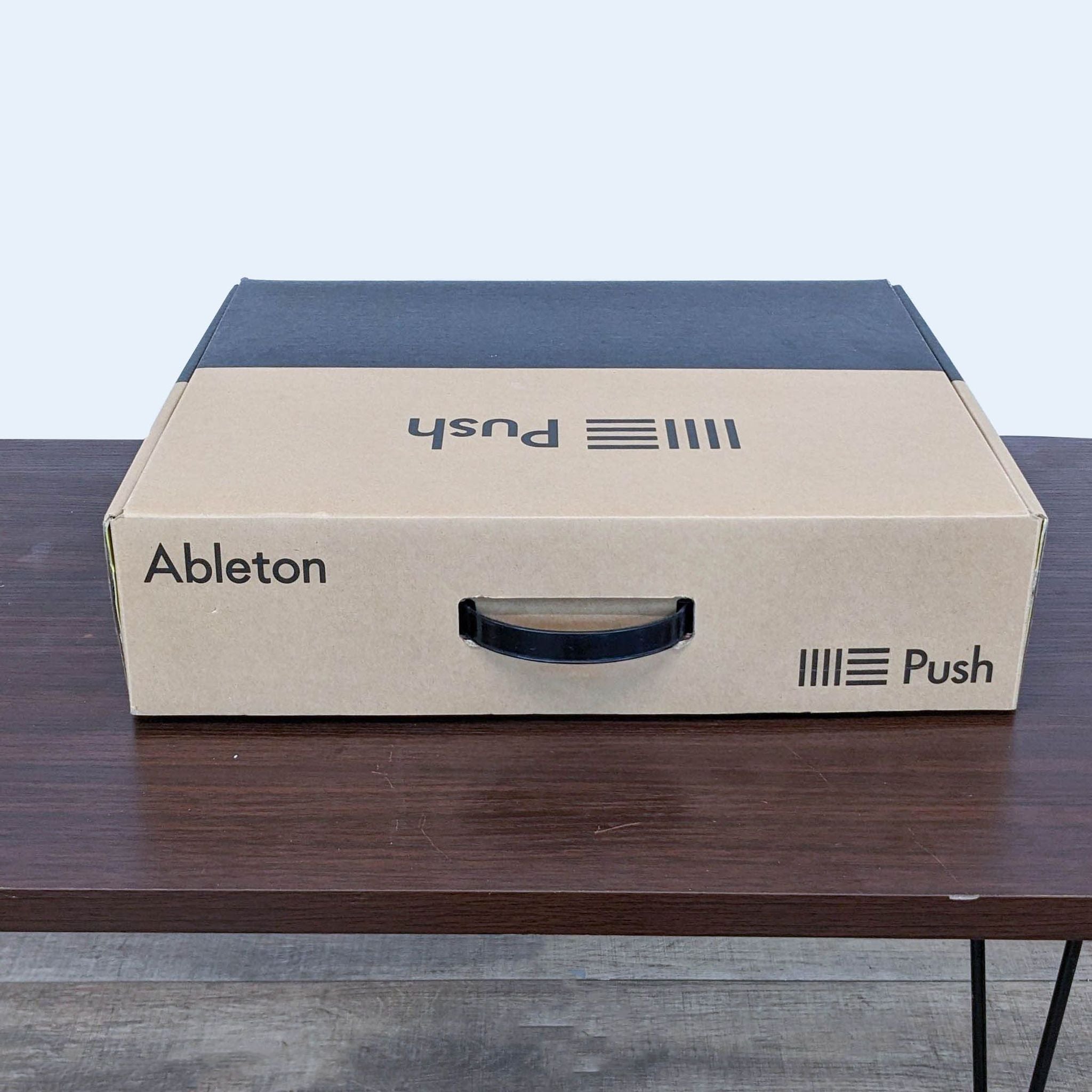 Cardboard packaging on table with "Ableton Push" label, indicating electronic music equipment inside.