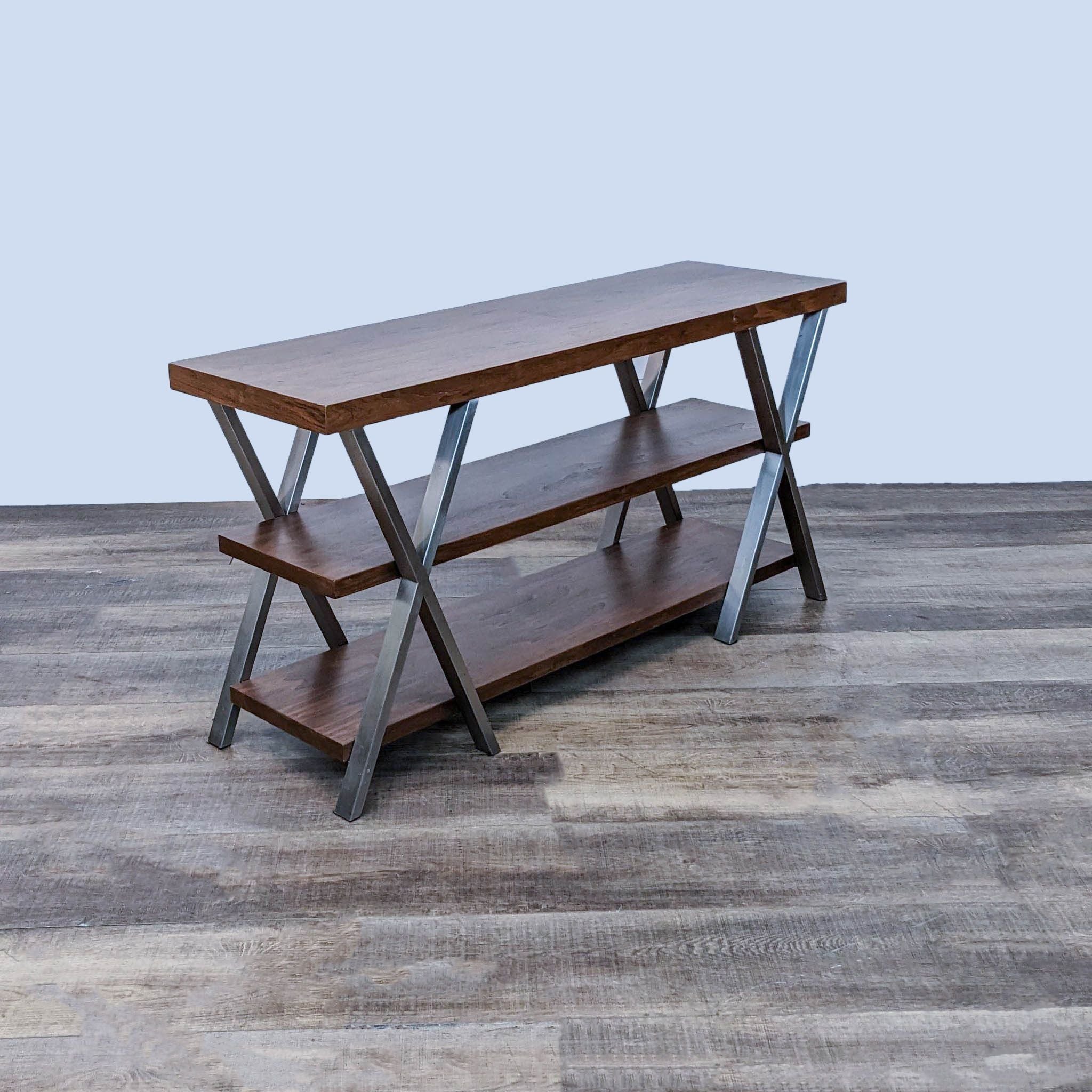 Reperch branded three-tiered side table with geometric side X framework and a chrome metal frame on a wooden floor.