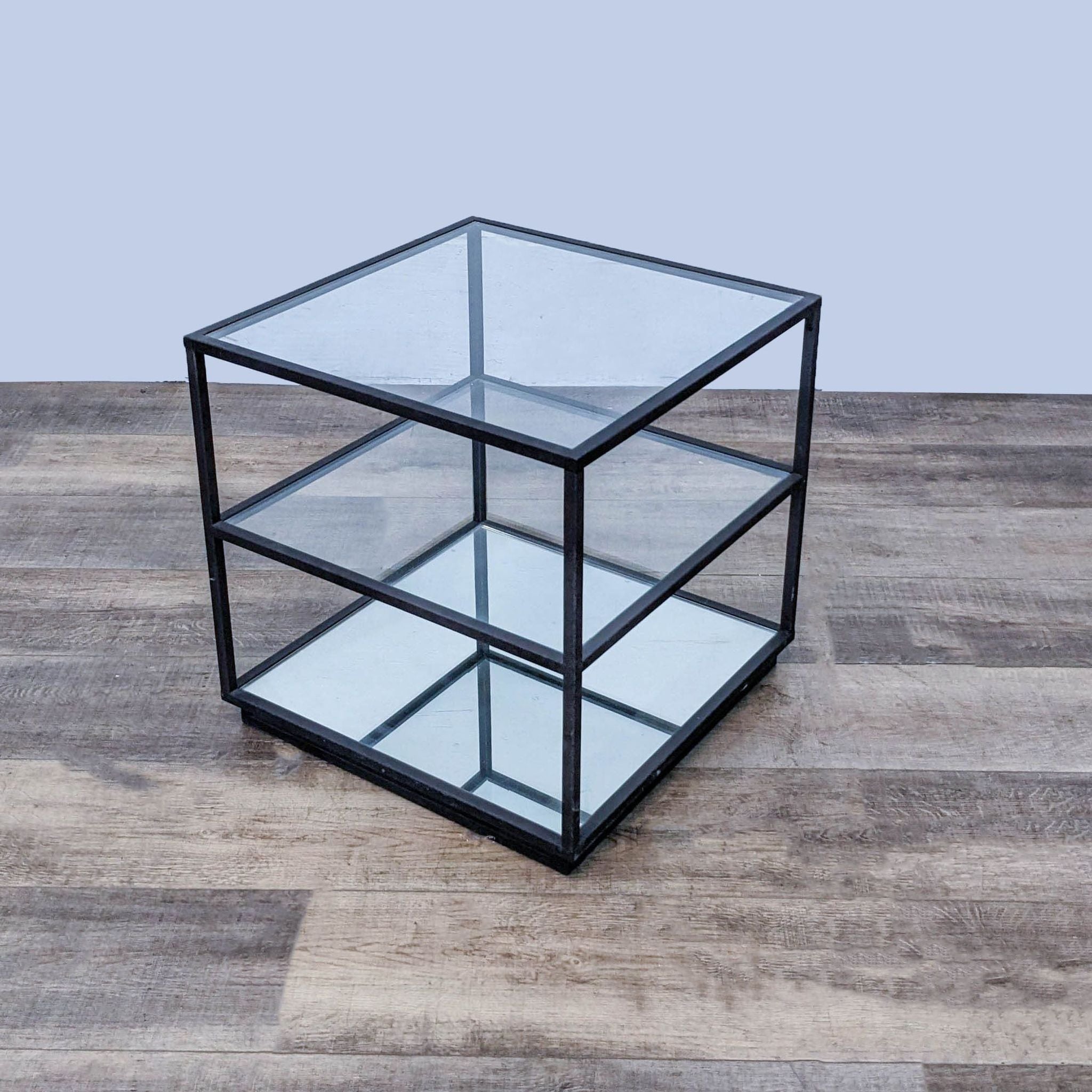 Reperch metal frame end table with glass top and two lower shelves, one mirrored, on a wooden floor.