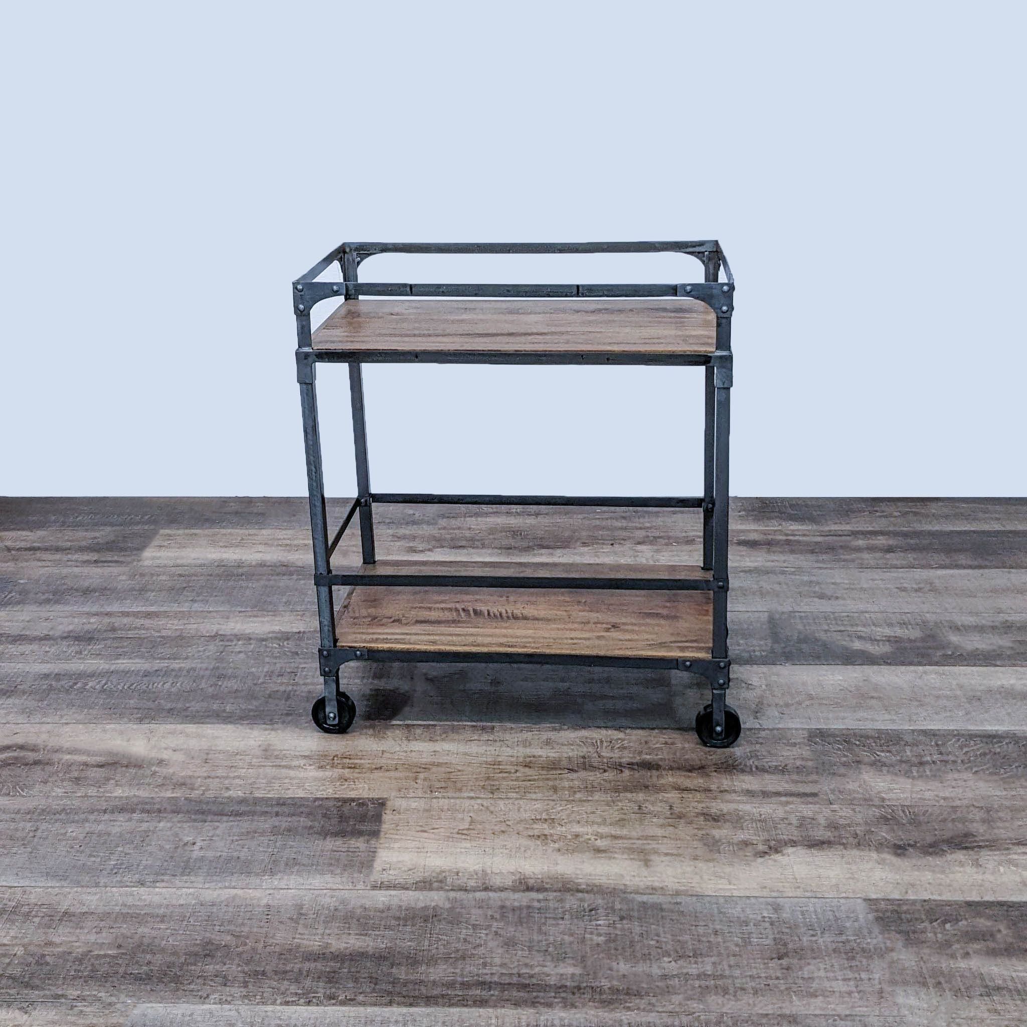 Cost Plus metal-framed cart with two wooden shelves on wheels, shown from the side, against a wood floor background.