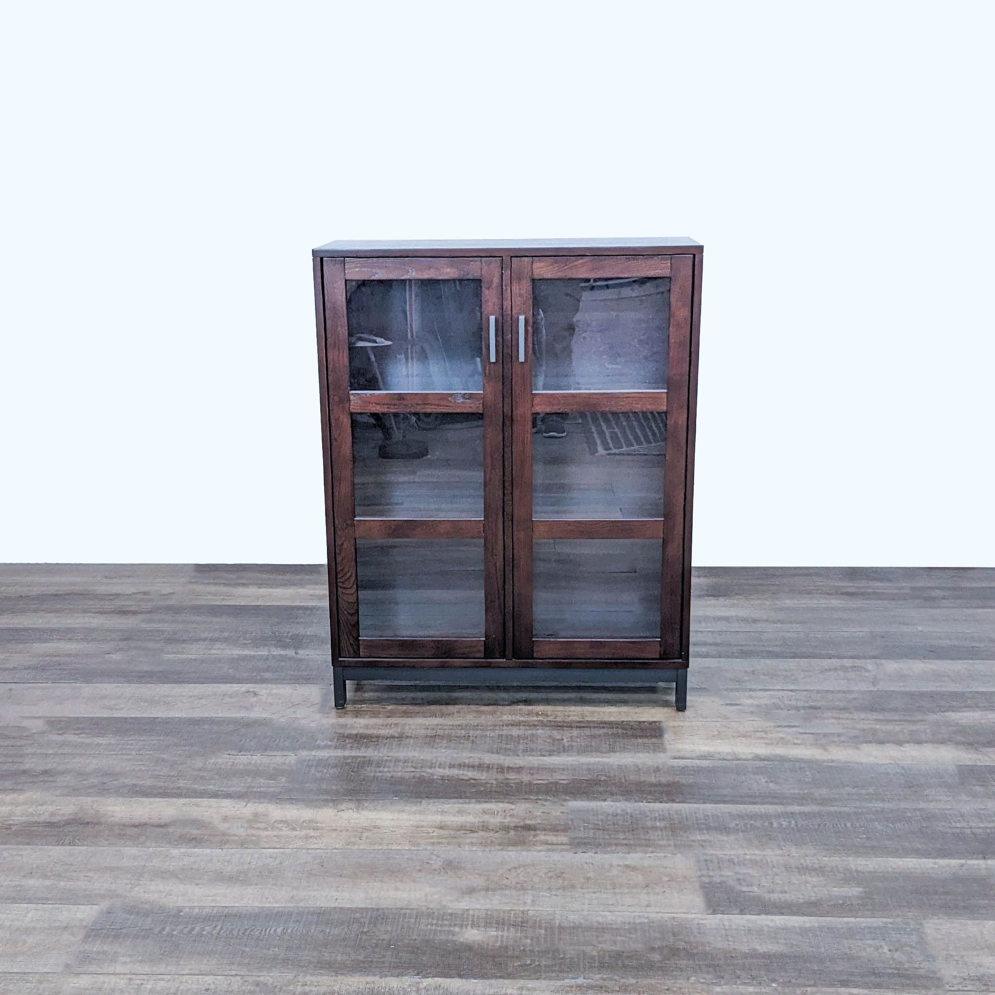 Crate & Barrel cabinet with glass doors and empty shelves against a wall.