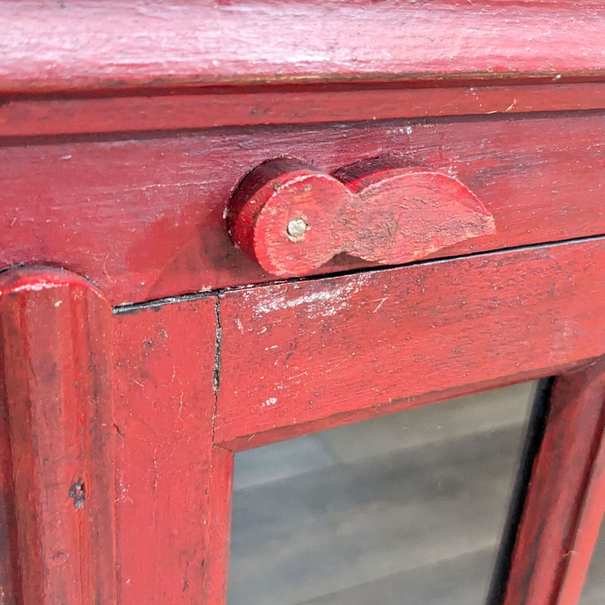 Red wooden cabinet detail showing texture and knob, exemplifying the craftsmanship of Crate and Barrel's furniture design. (Image 3)