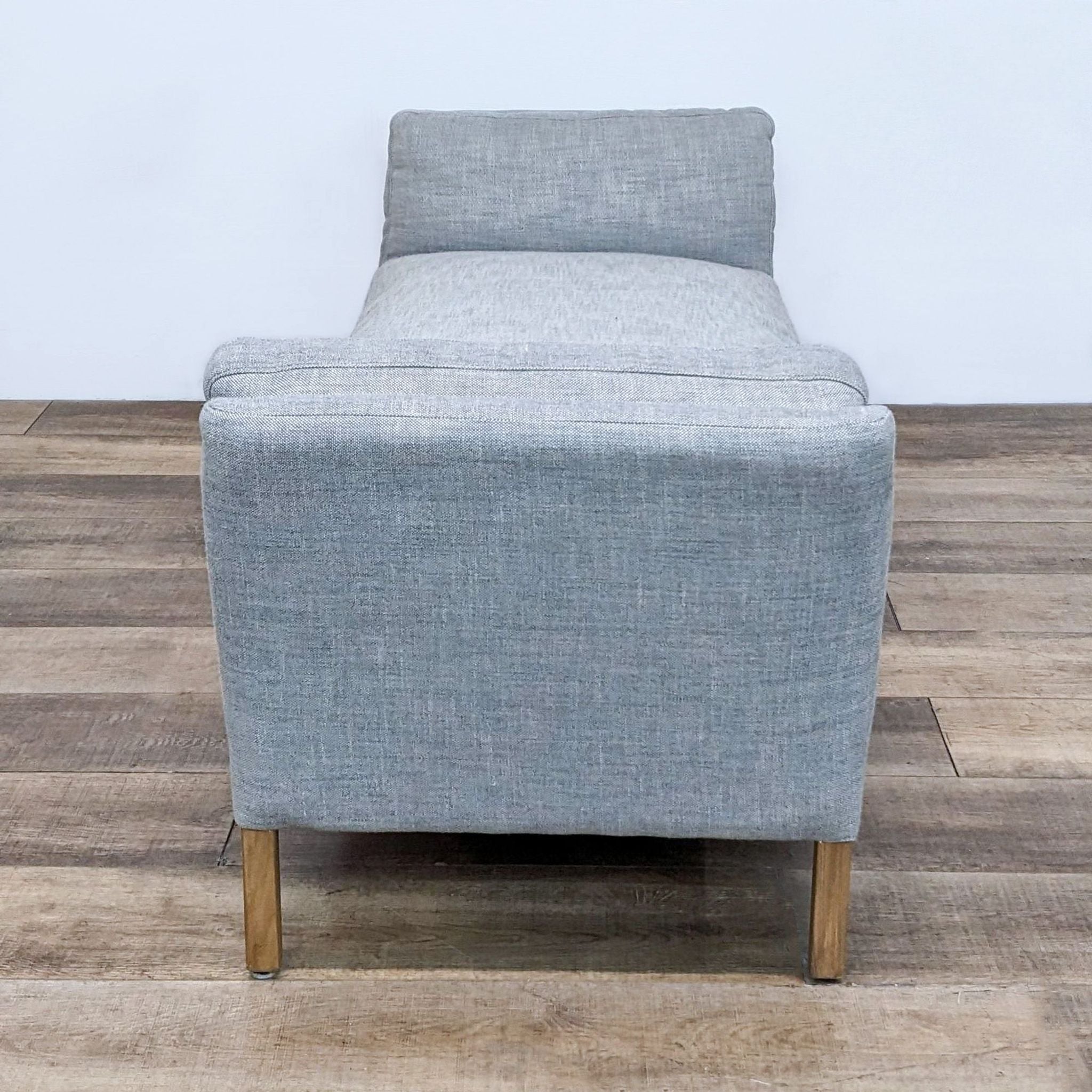 Restoration Hardware grey linen weave fabric bench with slope arms and wooden legs on a wooden floor.