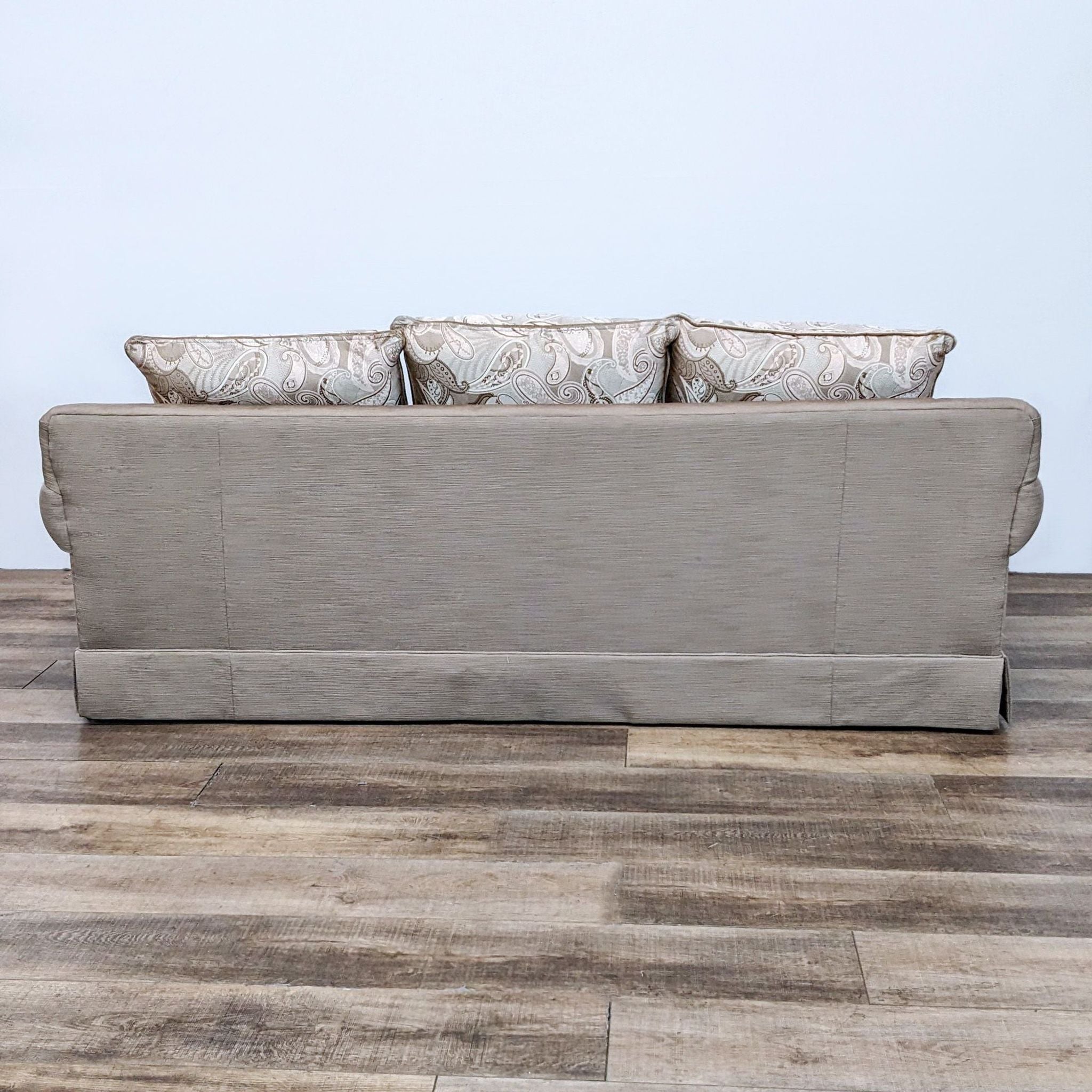 Reperch brand 3-seat neutral tone fabric sofa with patterned cushions and inverted skirt.