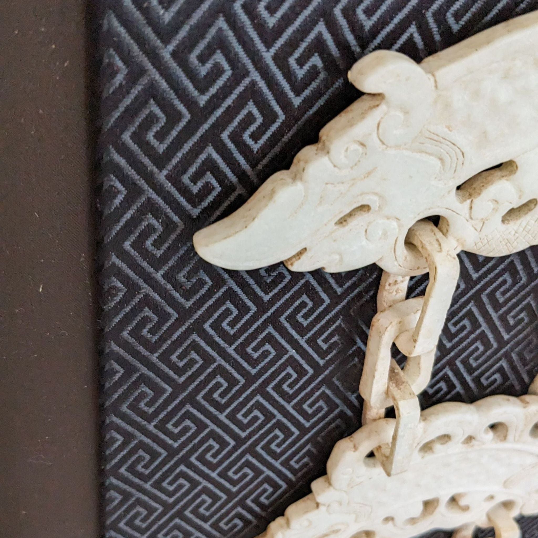 Close-up view of Reperch print showing detailed white jade carving against a contrasting intricate background.