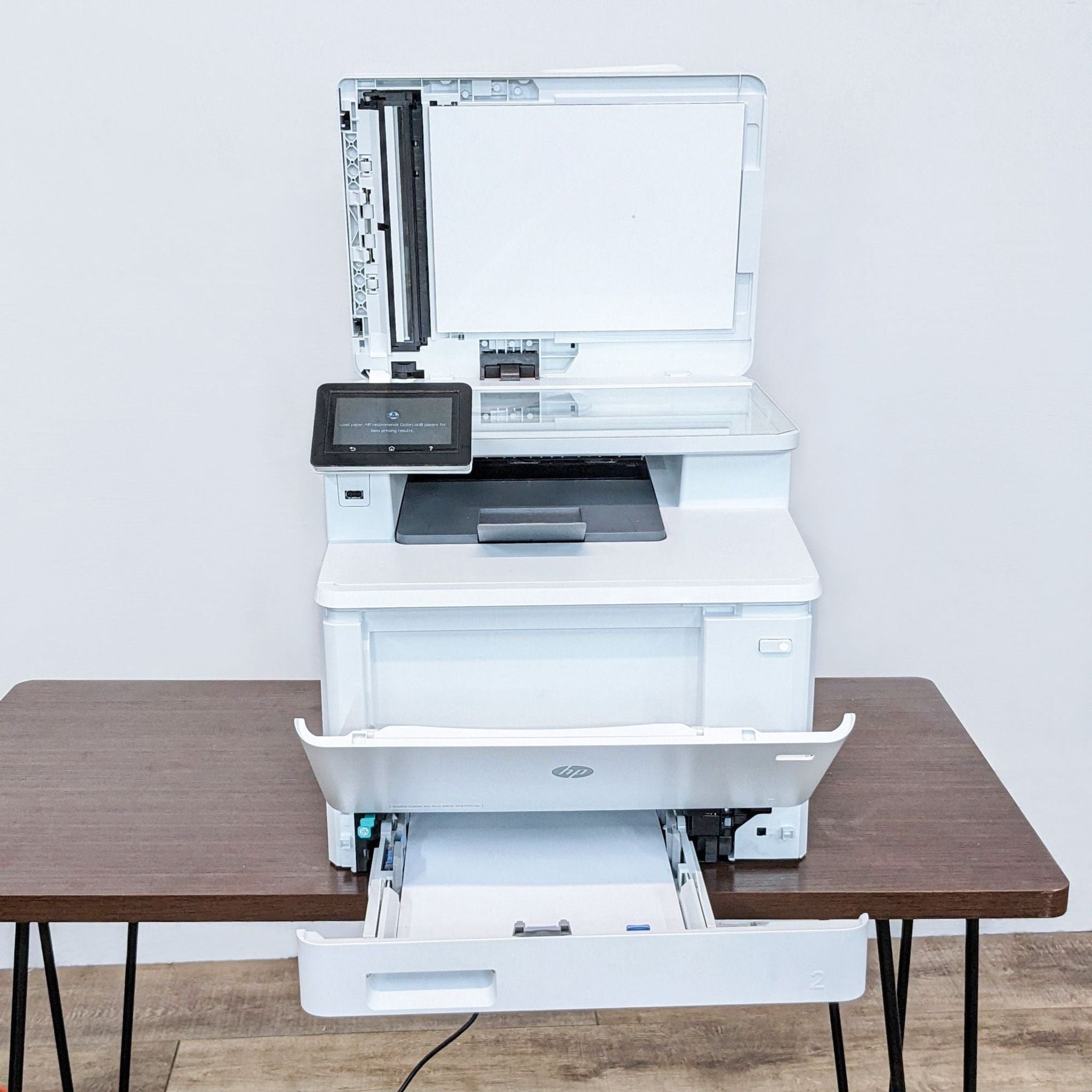 HP Color LaserJet Pro MFP open showing paper tray and scanner, with model label M477fnw.