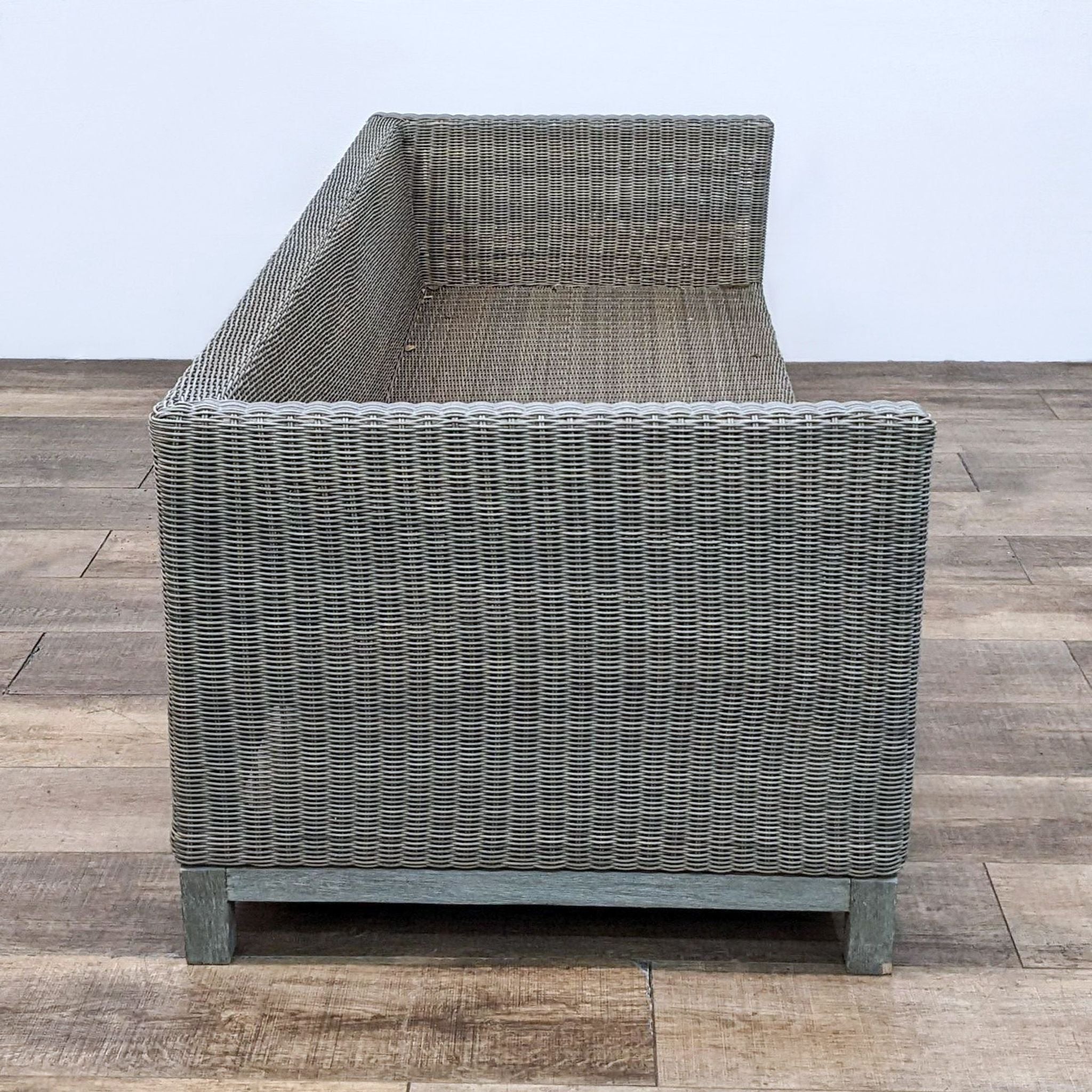 Alt text: Restoration Hardware resin wicker outdoor armchair with modern teak wood frame on a wooden floor.