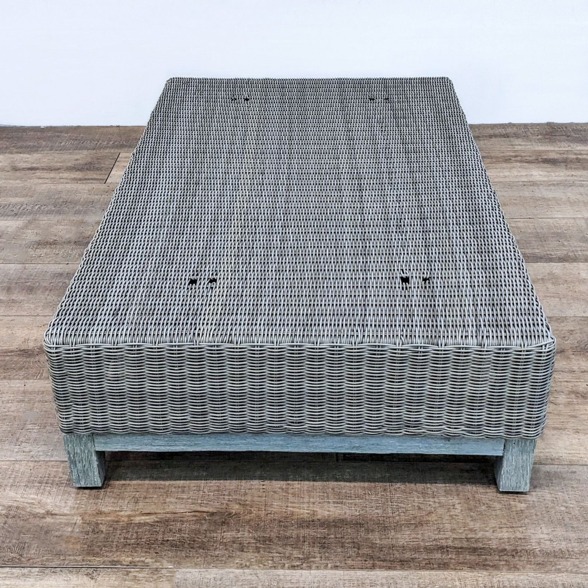 Restoration Hardware low-profile woven wicker coffee table on a weathered wooden base.