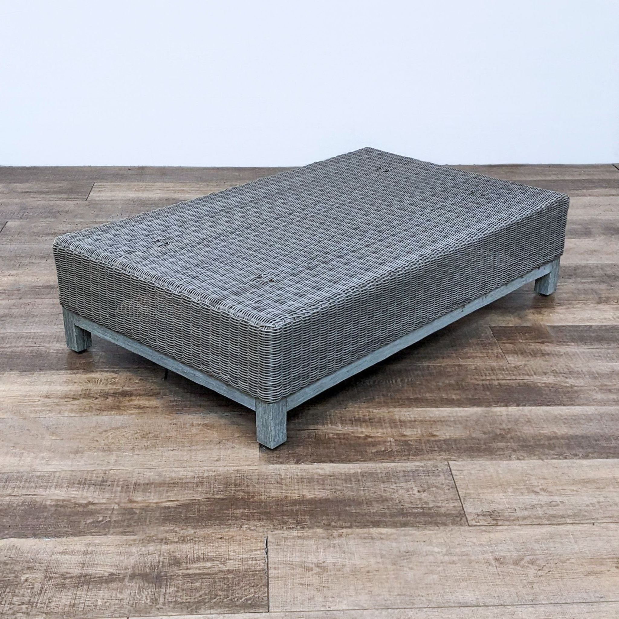 Woven wicker rectangular coffee table by Restoration Hardware, featuring a low and wide design with a distressed wood foundation.