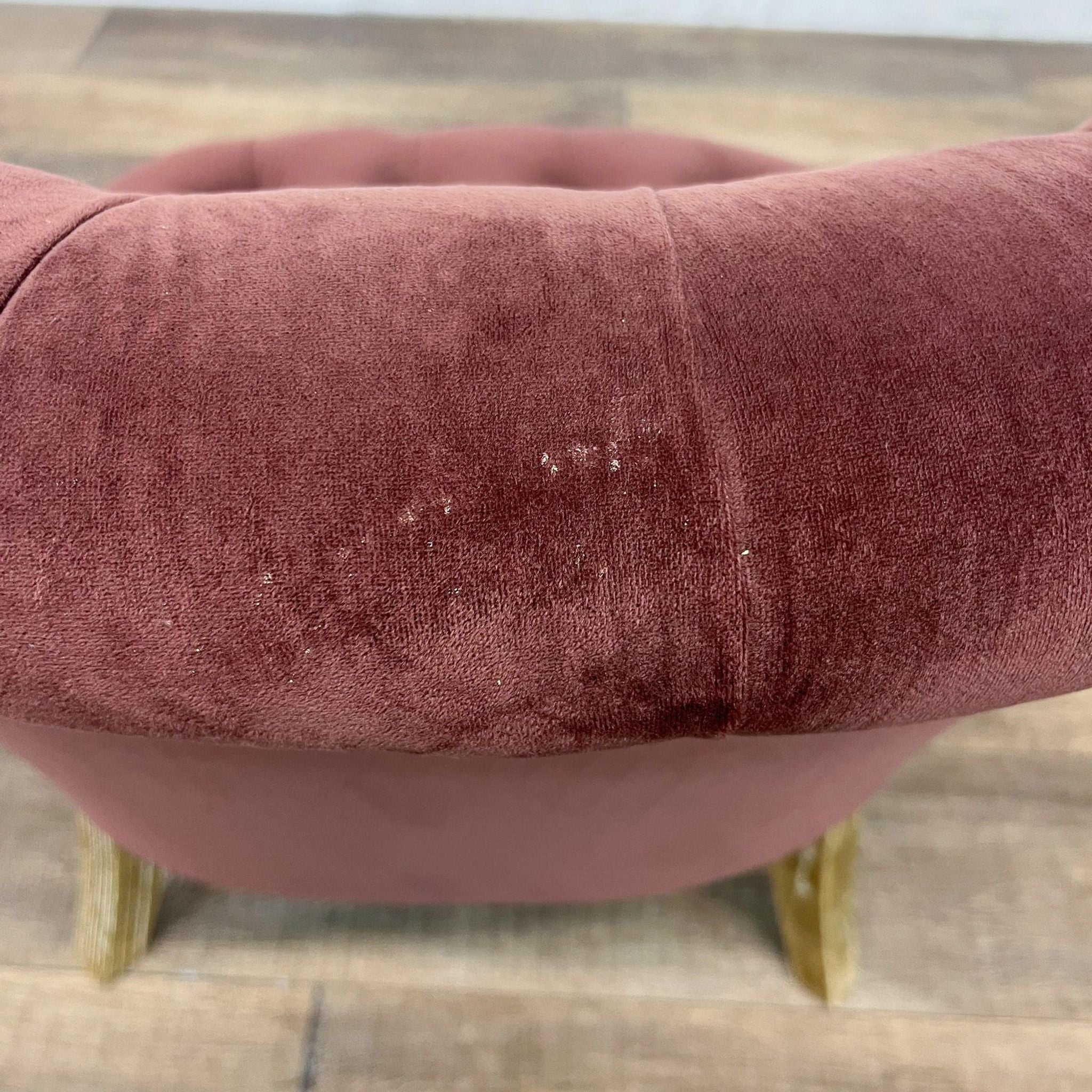 Cost Plus accent chair with curved tufted velvet upholstery and wooden turned legs with casters, in a dusty rose color.