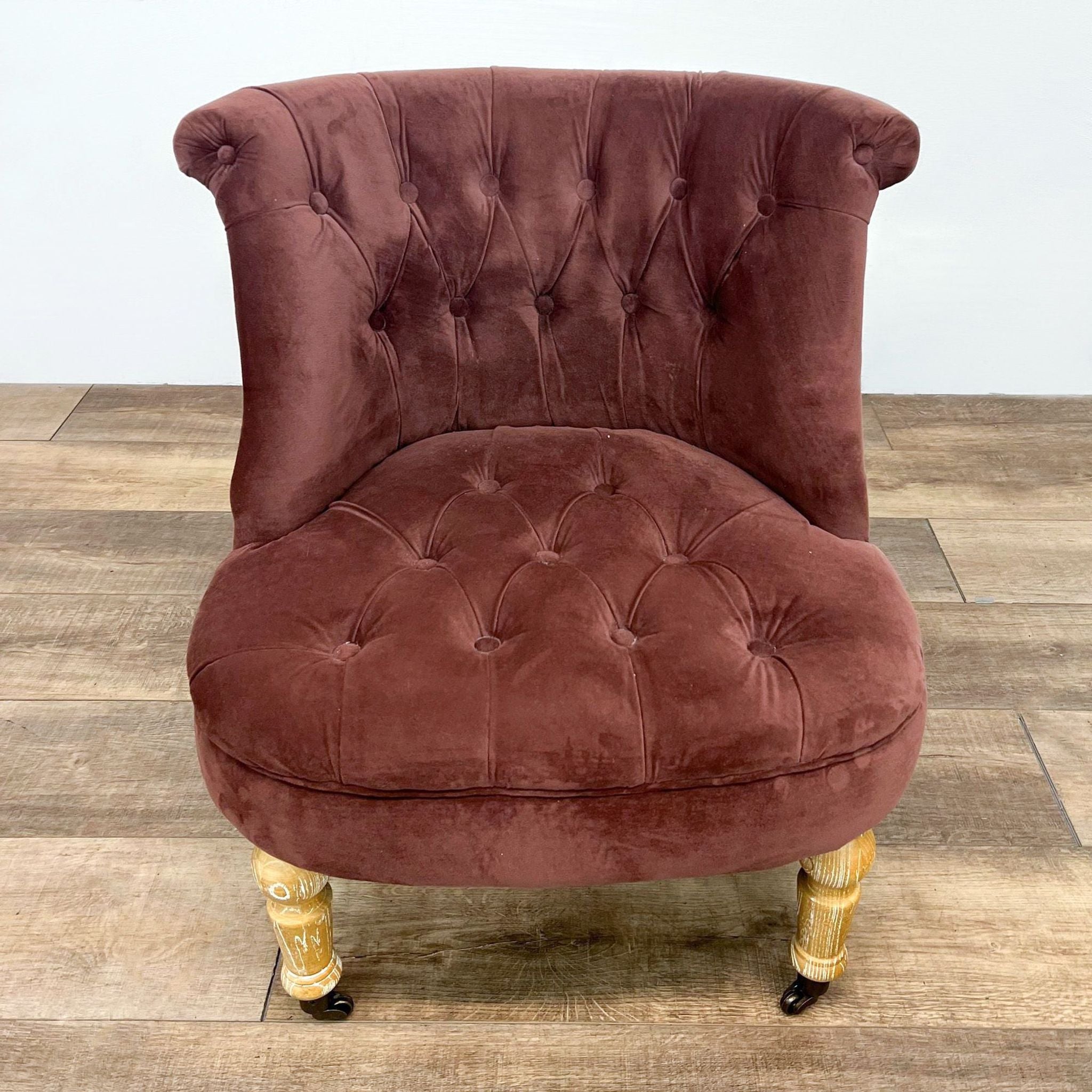 Cost Plus tufted velvet accent chair with curved back and wood legs with casters, in a lounge setting.