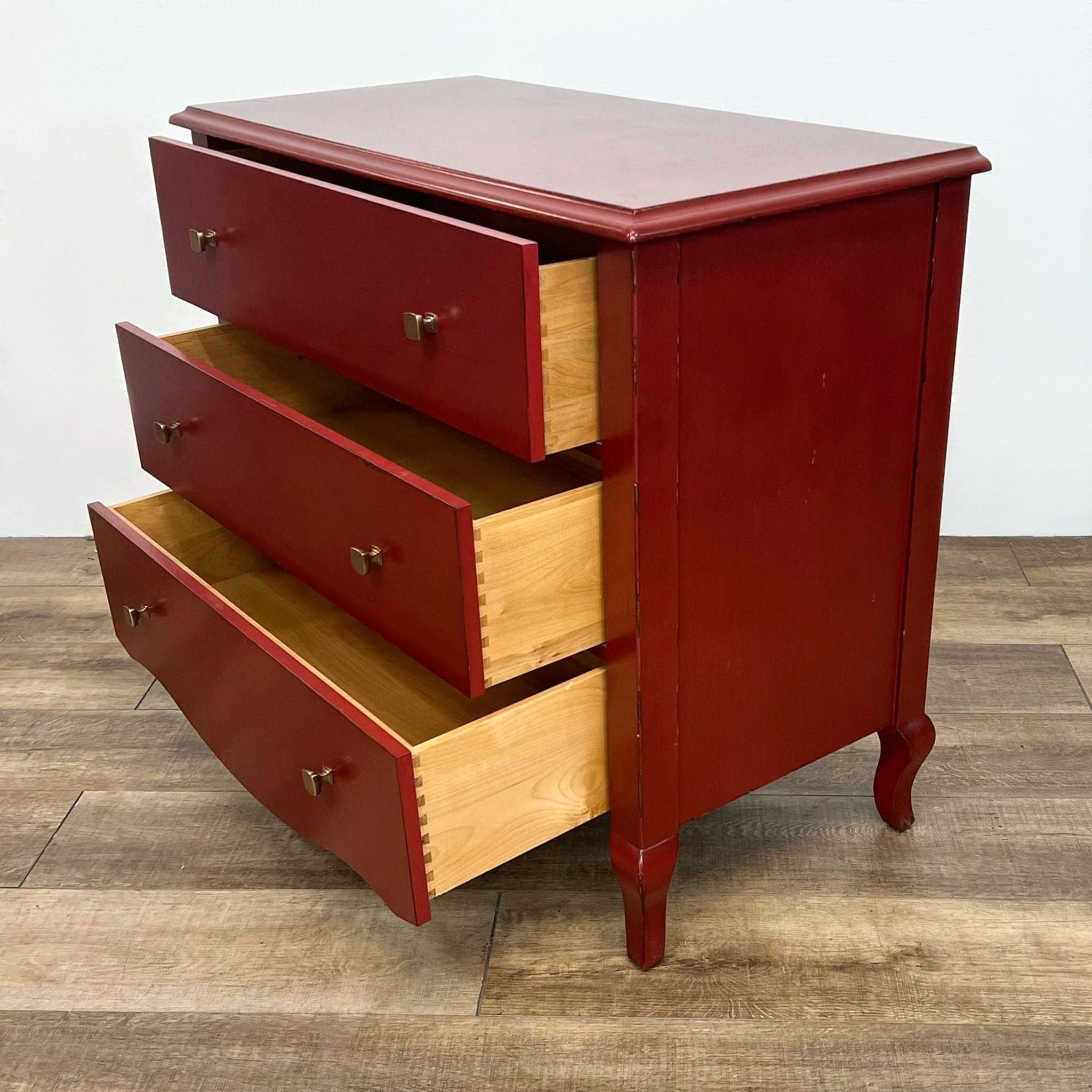 Pottery Barn red Luca 3-drawer dresser with open drawers revealing the inside, on a wooden floor.